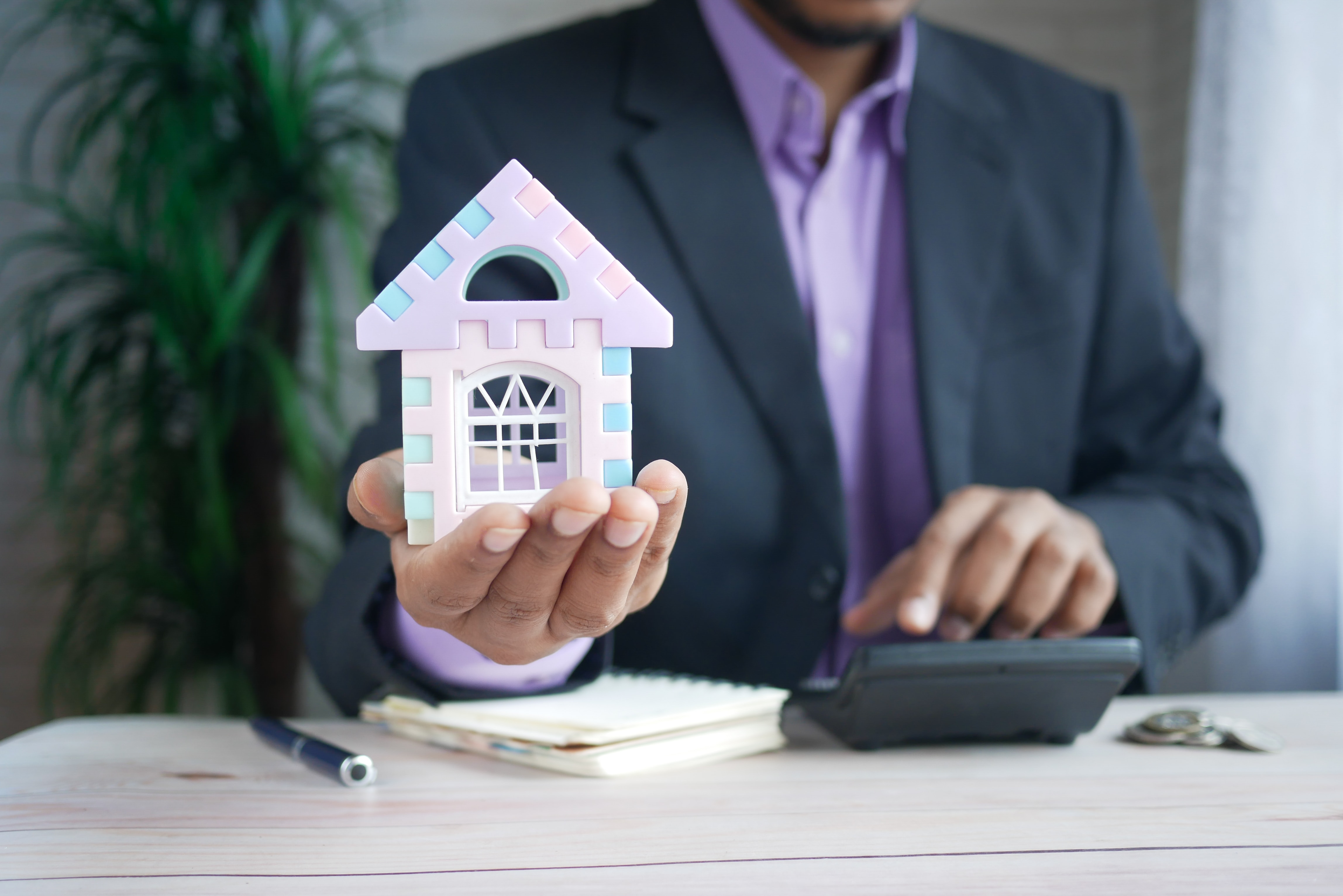 Loan officer or realtor with a calculator and a small house.