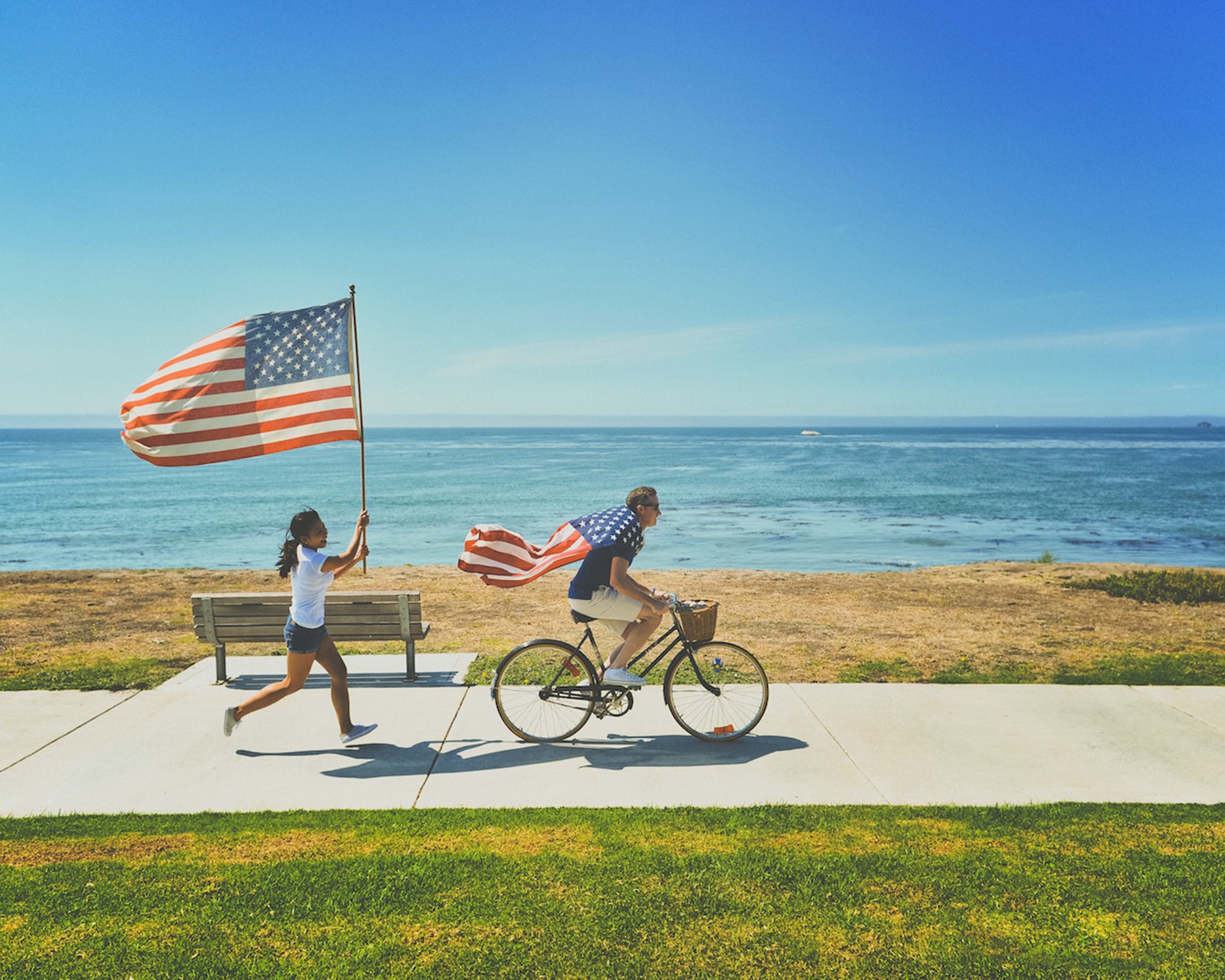 Person running with a US flag and person riding a bike with a US flag