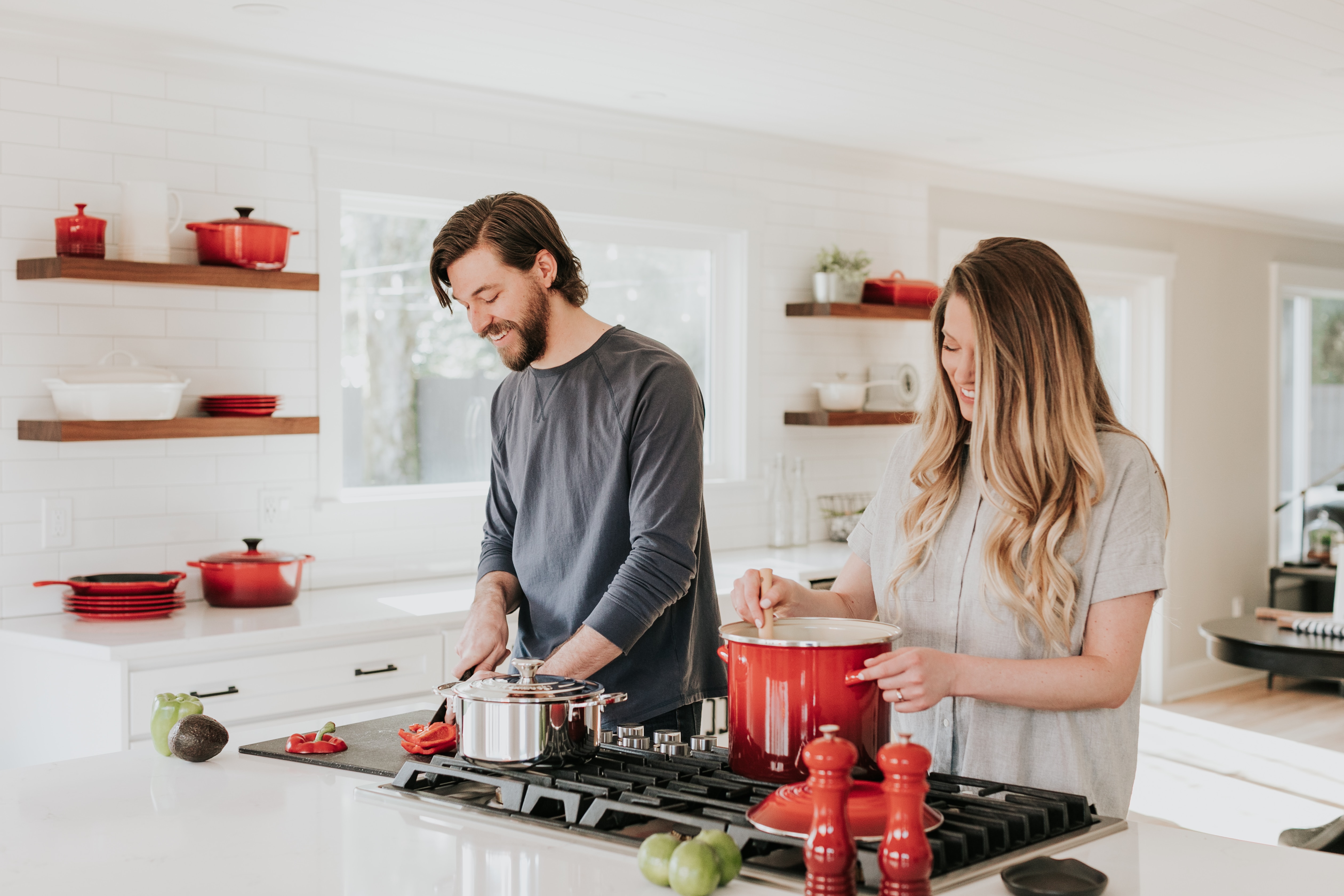 A man and woman cook at the stove in their home kitchen.