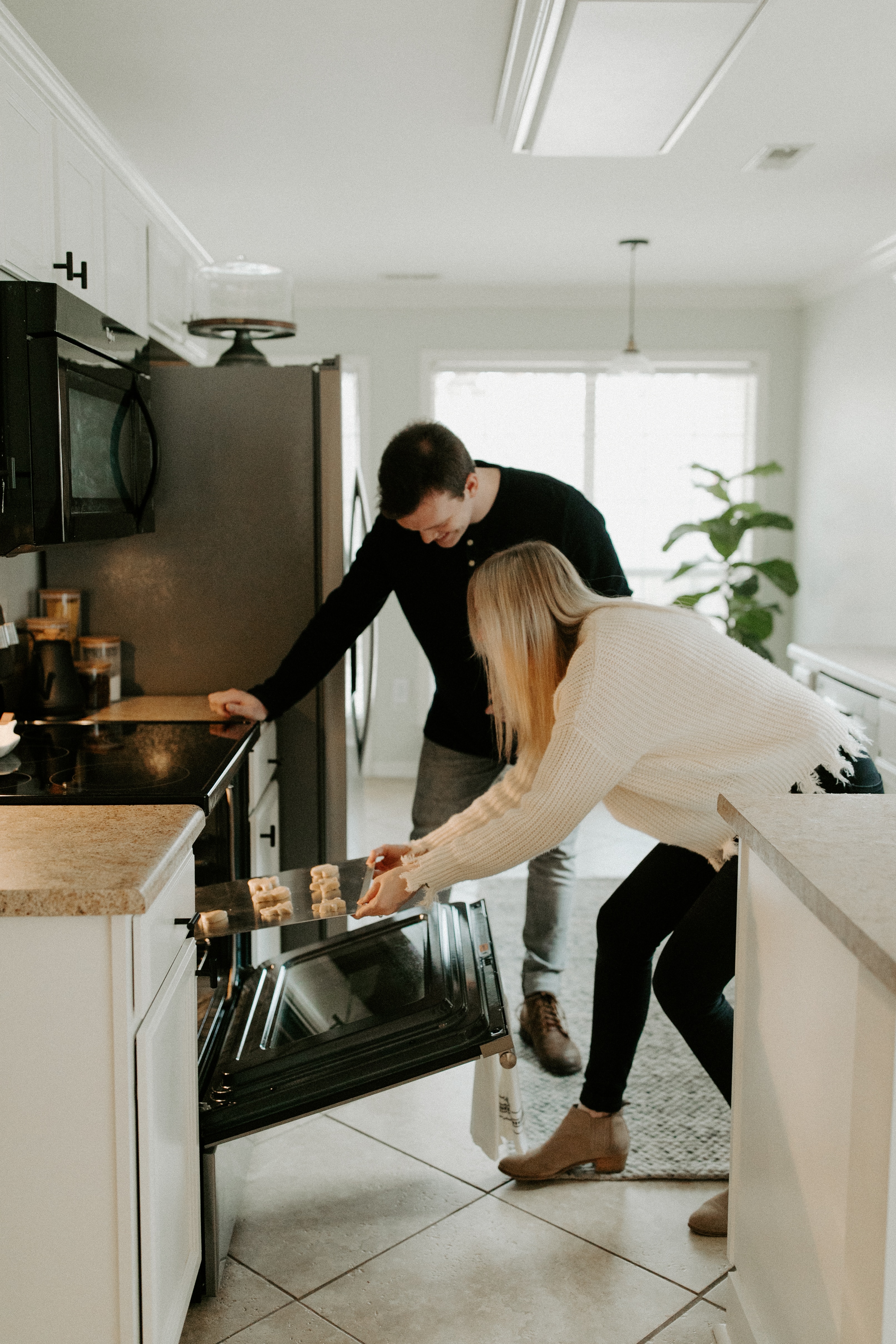 Man and woman at home putting cookies in the oven.