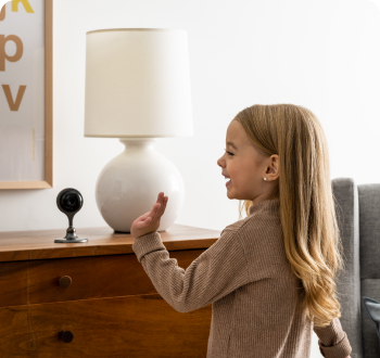 little girl waving at indoor camera