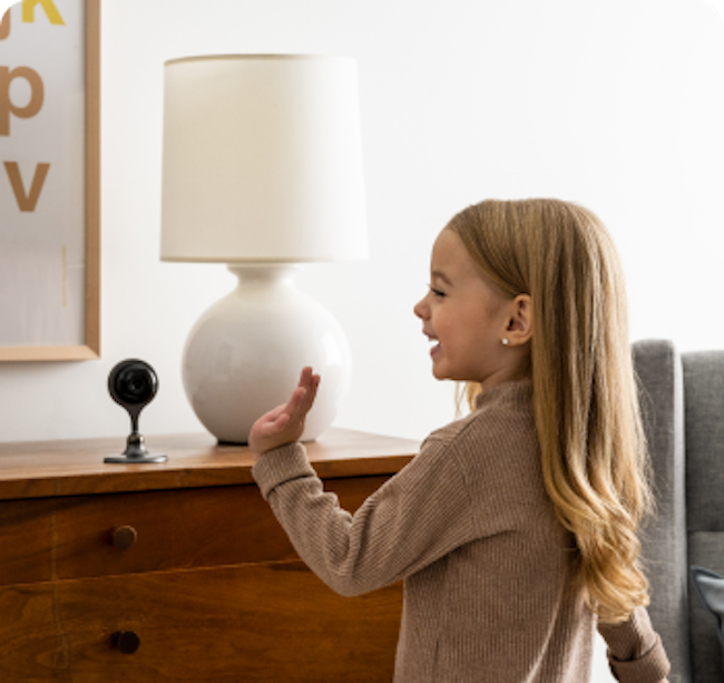 little girl waving at indoor camera
