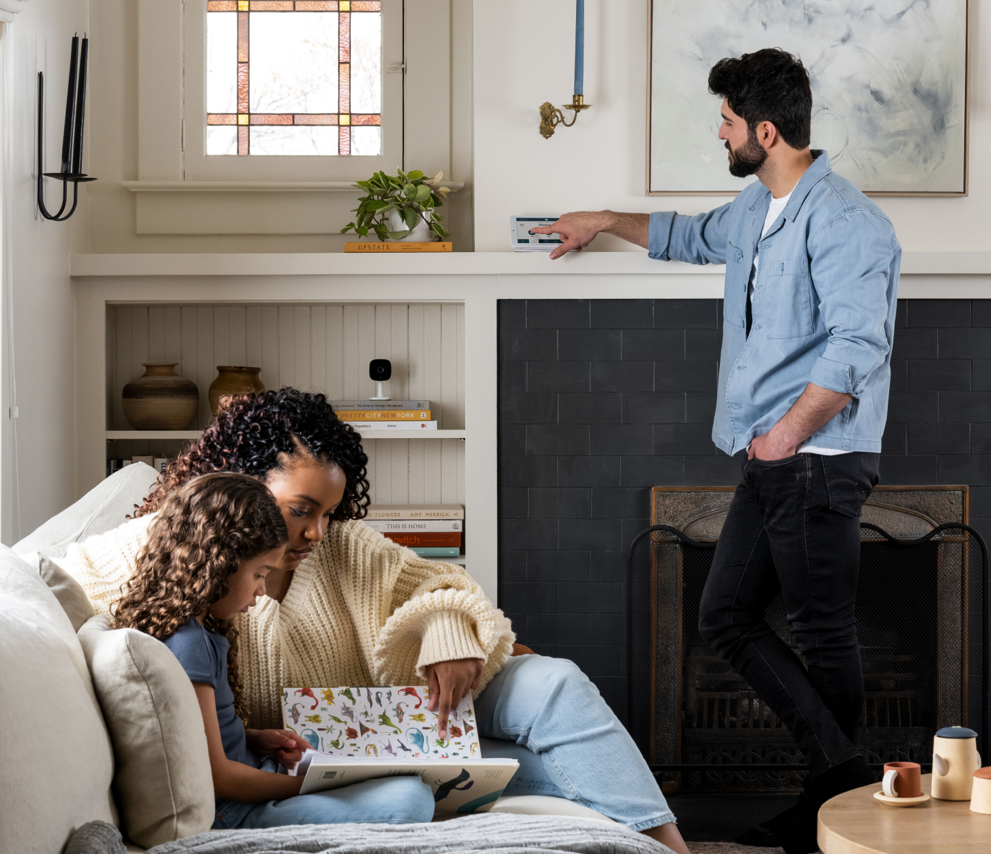 Man interacting with alarm panel hub in room with family