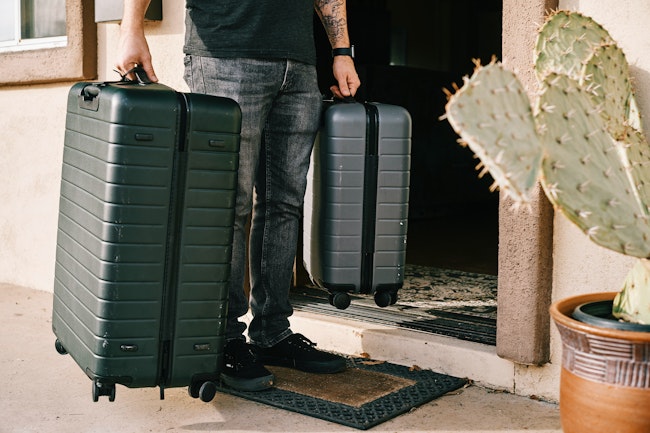 A guest comes through the front door with luggage.