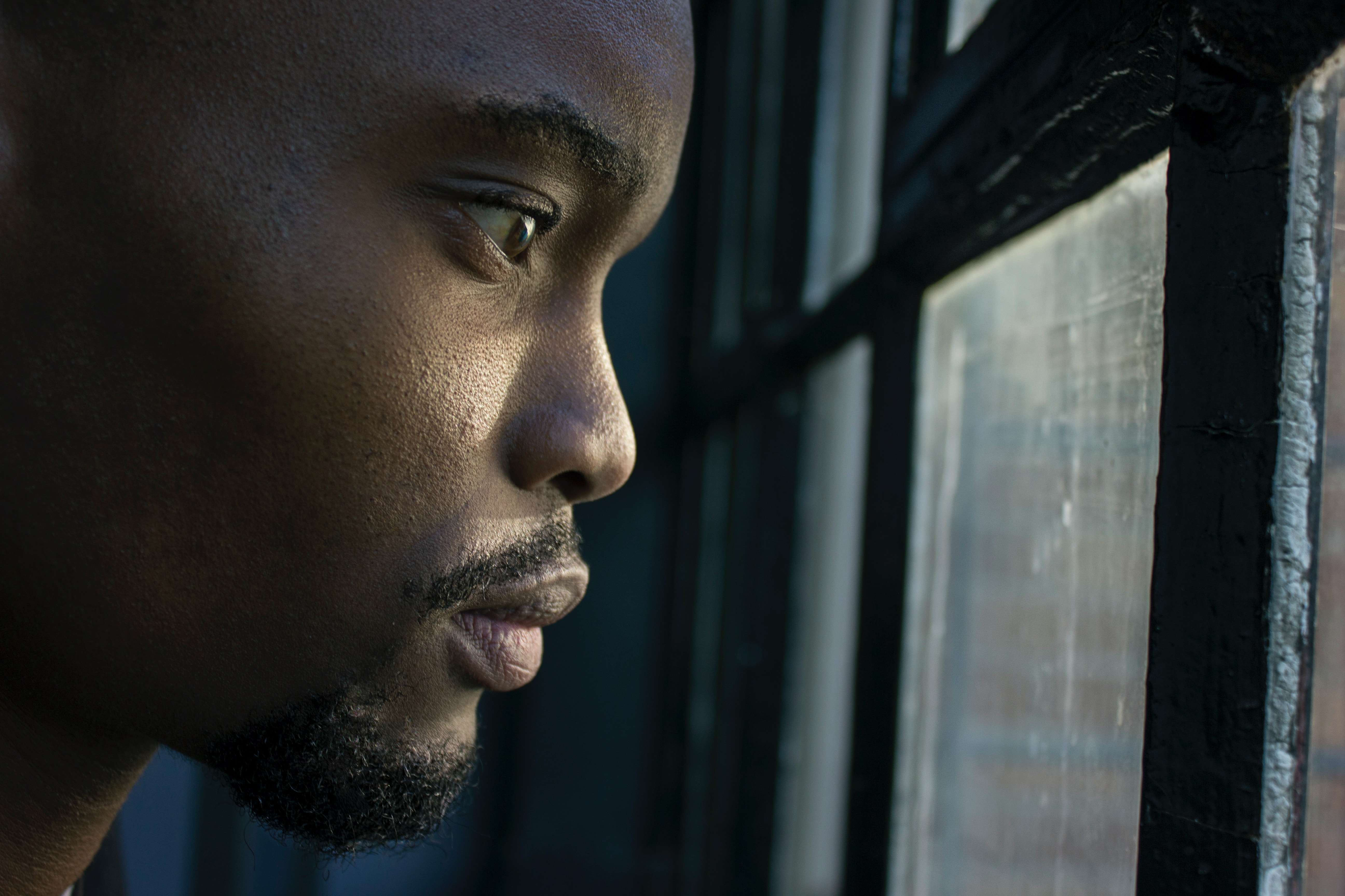 Man with insomnia looking out a window at night.