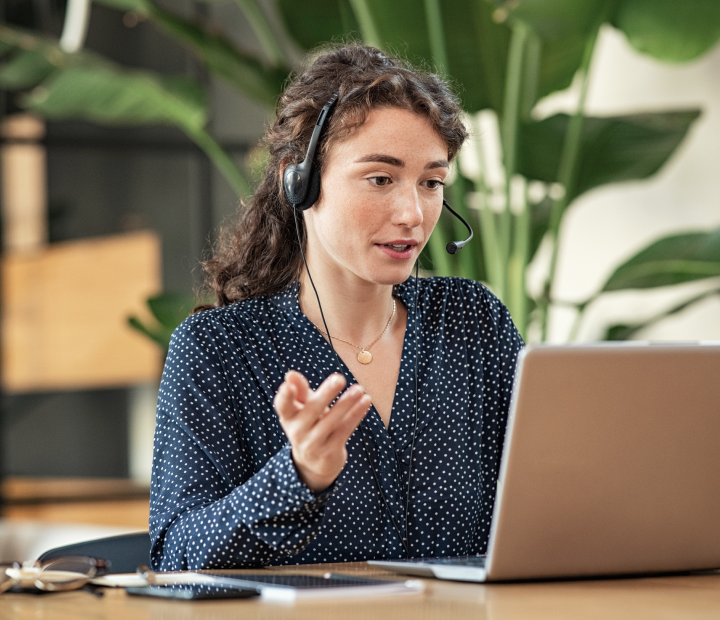 Woman on a headset phone looking at laptop