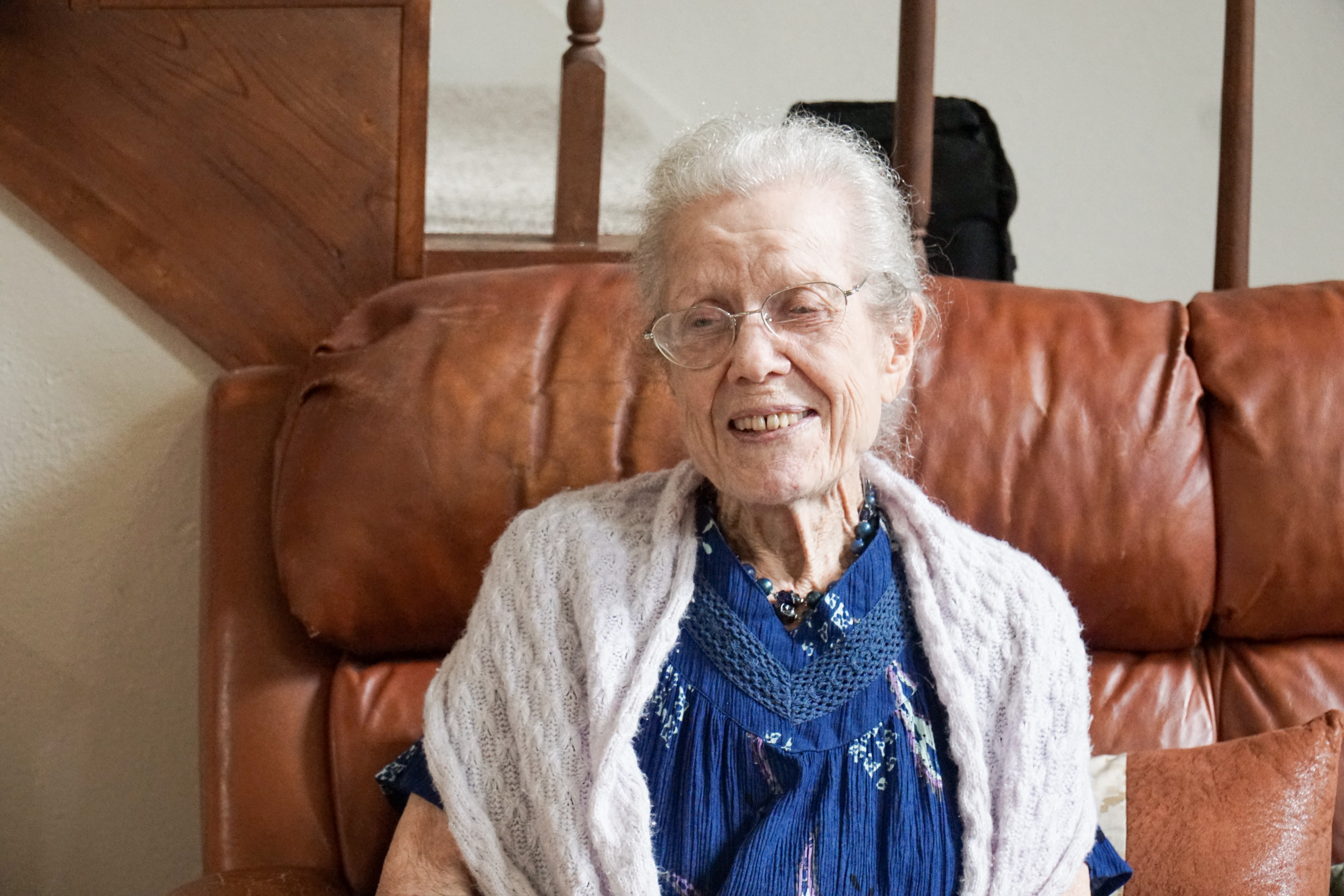 Elderly woman sitting on a couch in her home.