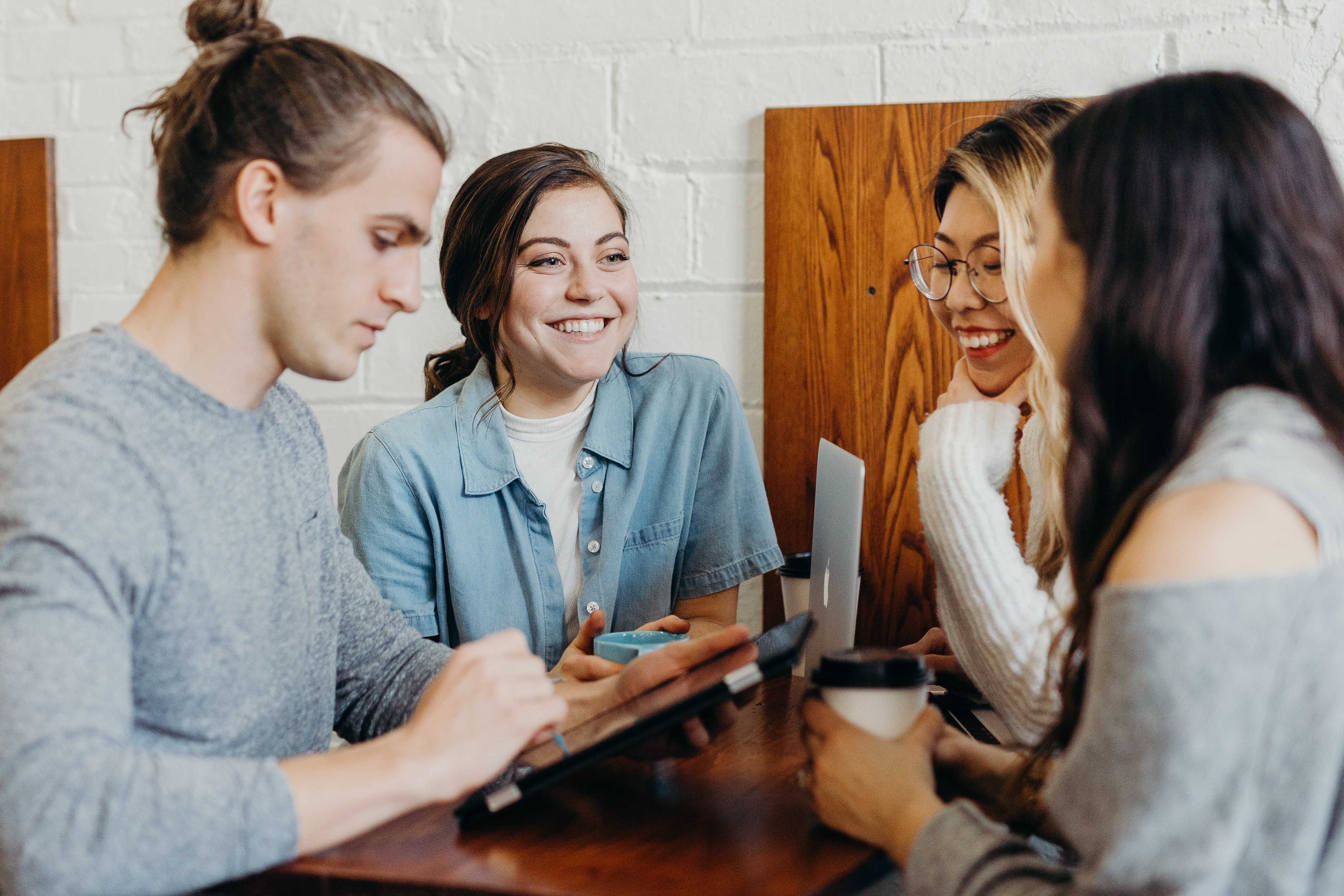Group of Millennials using tech at a coffee shop.