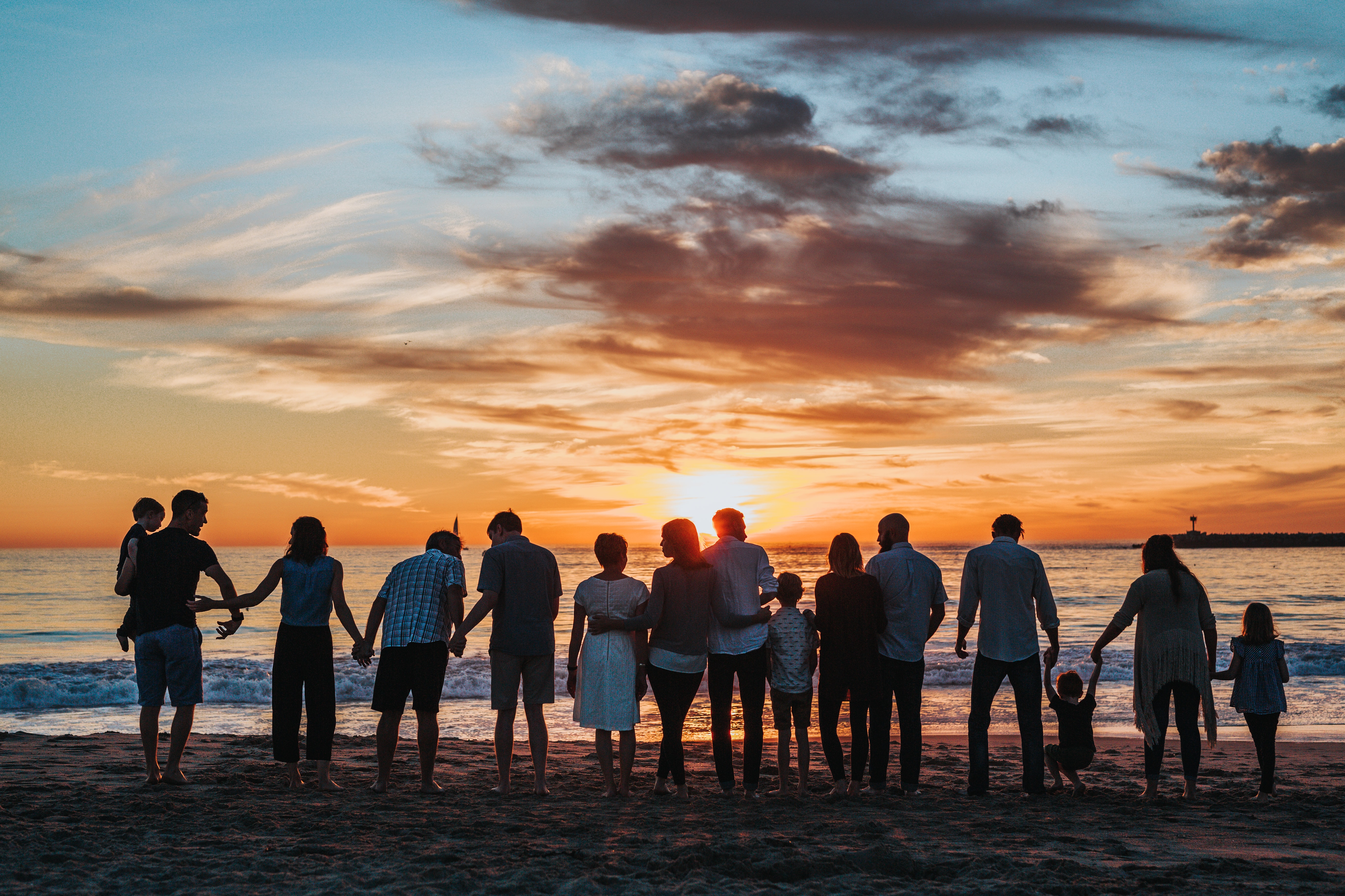 Generations of family in line on the beach at sunset for a family photo.