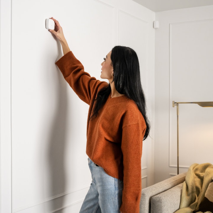 Sticking a Cove window sensor in place during a DIY install