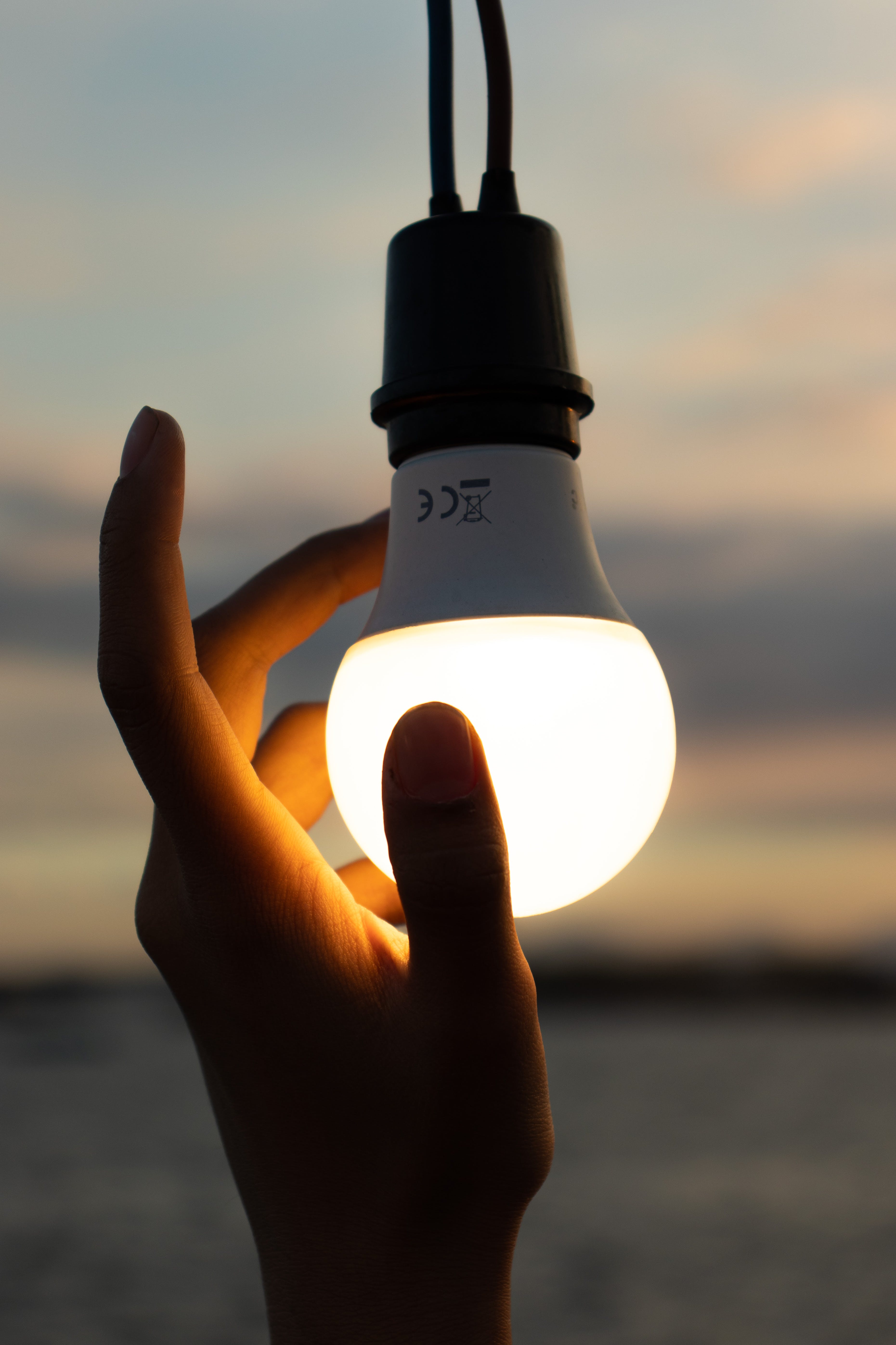 Smart light bulb lit up with a hand.