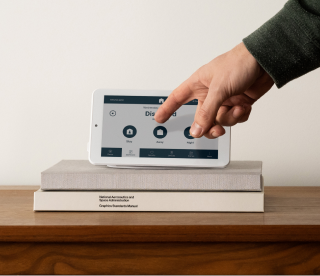 Person arming alarm system through alarm panel on table