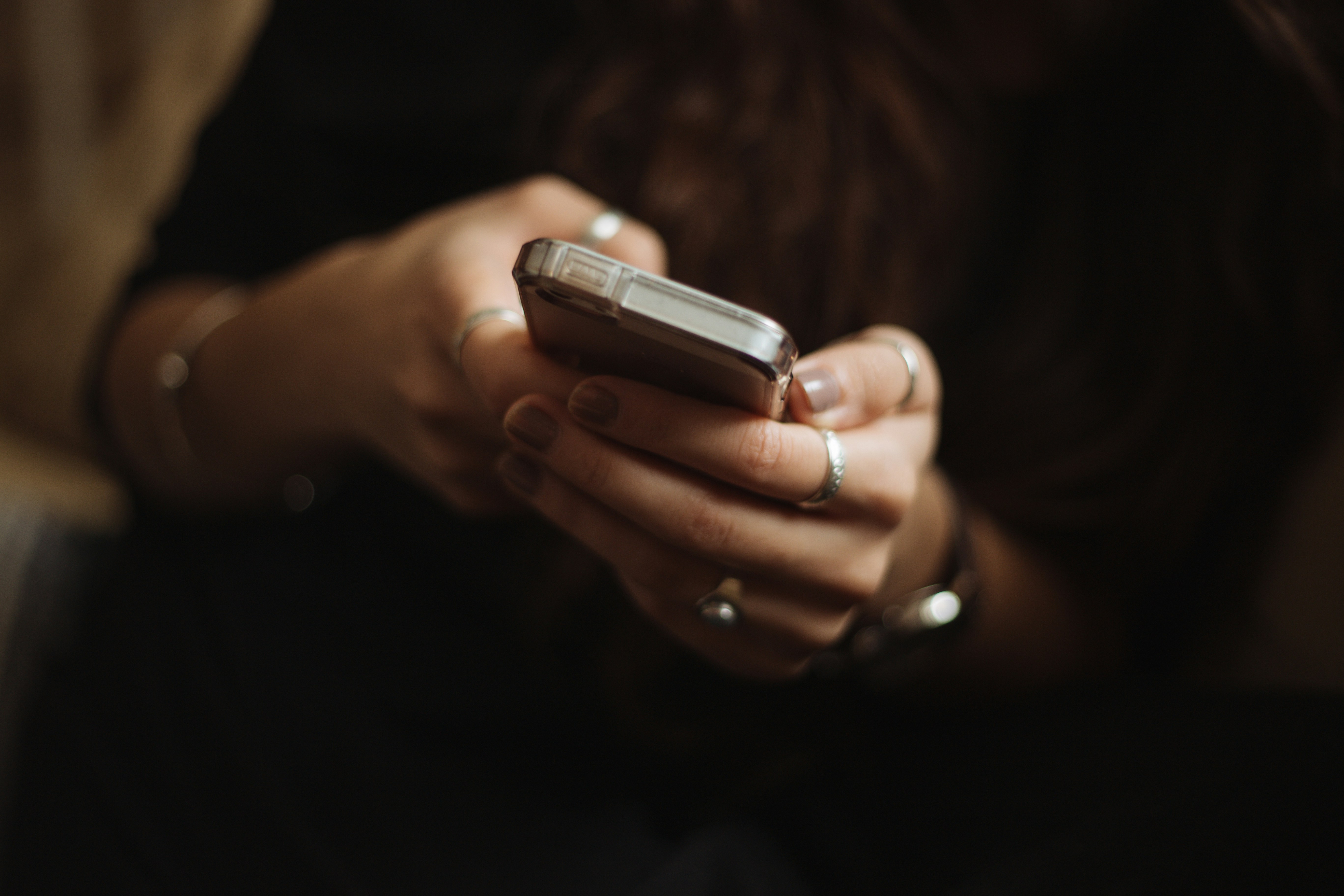 Woman holding a phone and looking at the apps while away from home at night.