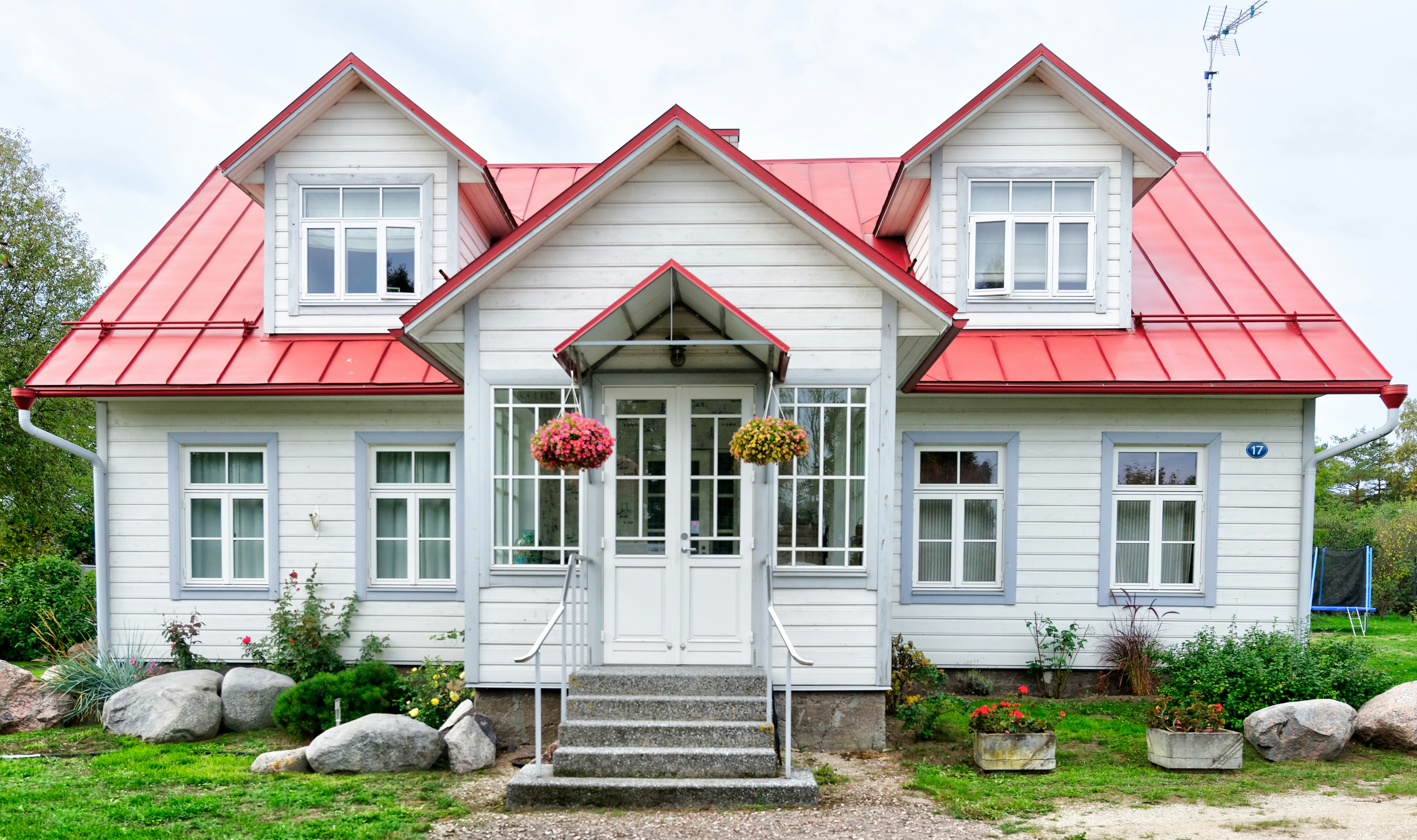 White home with a red roof with green landscaping.