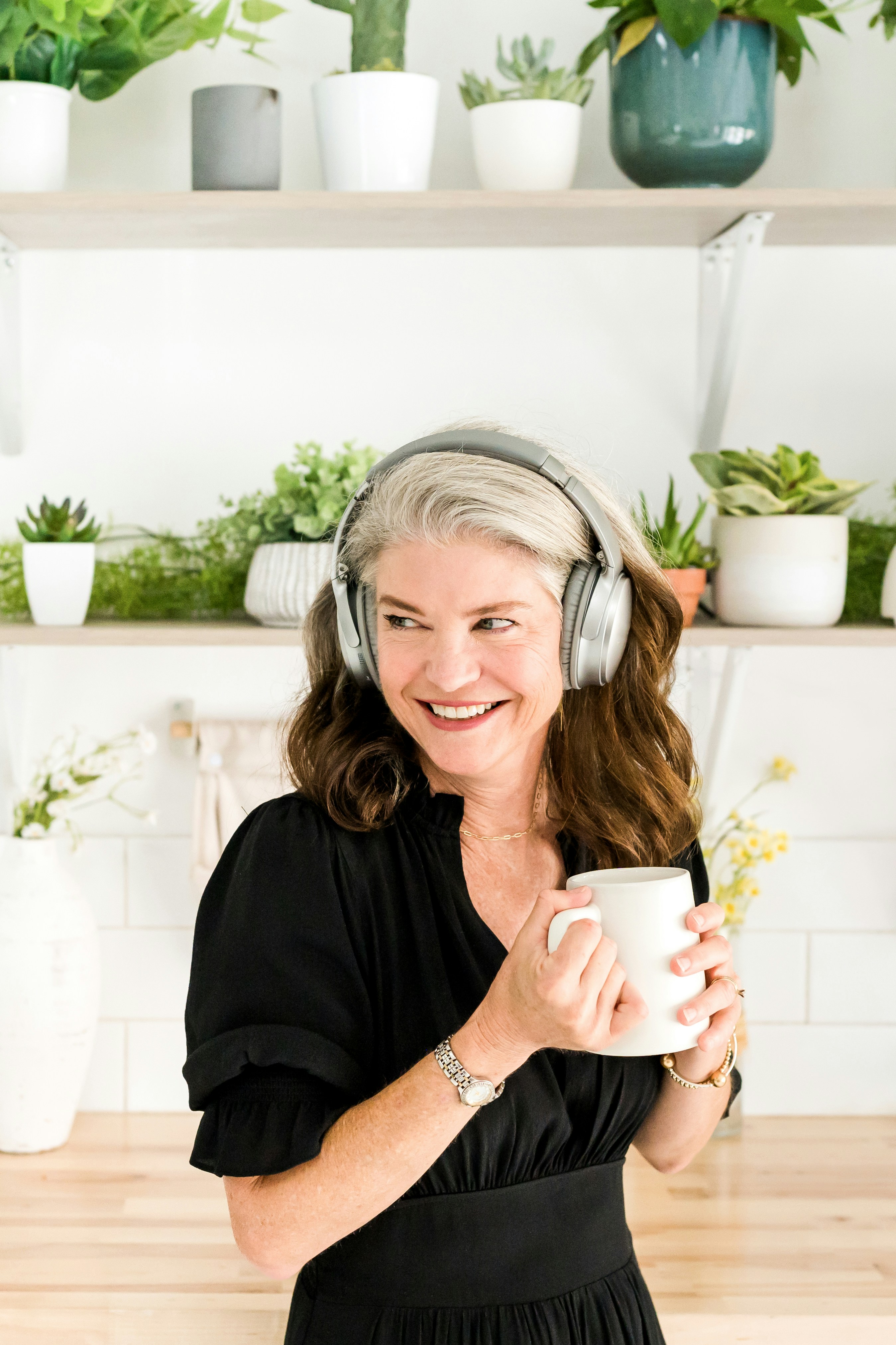 Woman holds coffee while listening to a podcast with headphones.