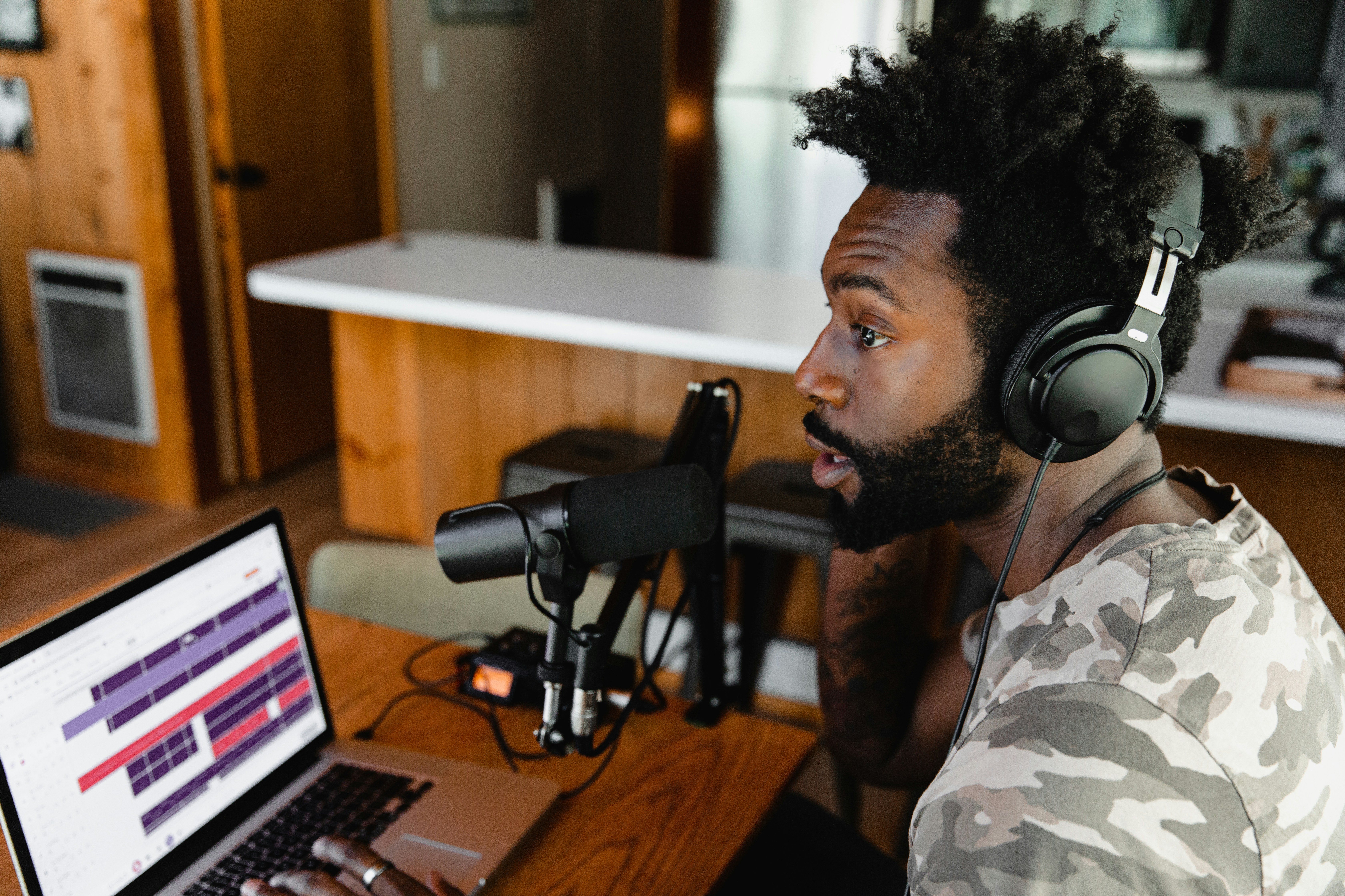 Man speaks into a microphone connected to his computer as he voices a podcast.