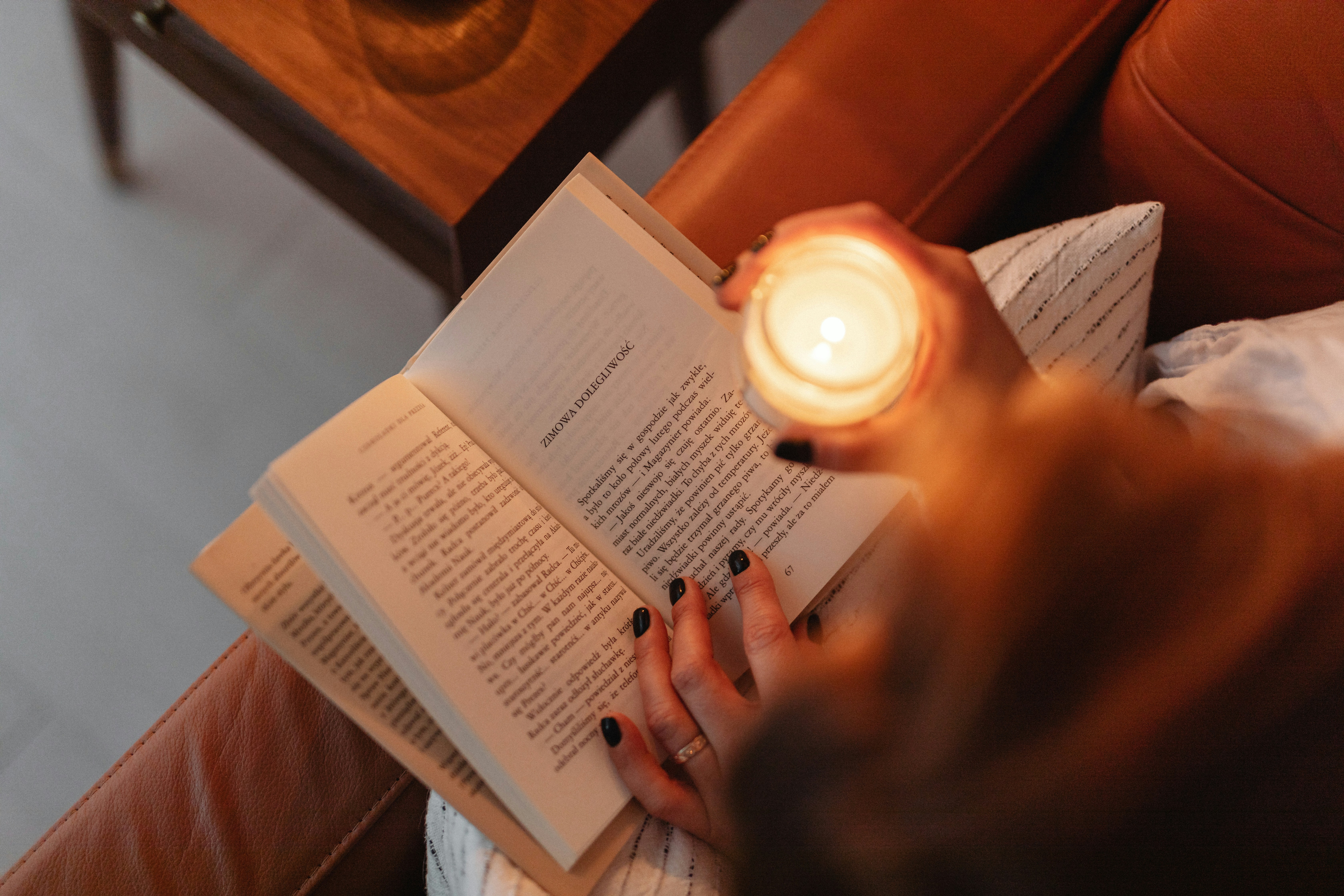 Woman reading a book by candlelight during a power outage.