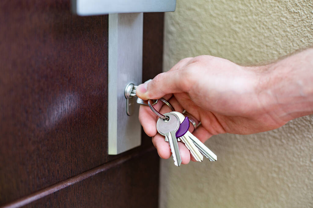 Man locking his front door with a set of keys.