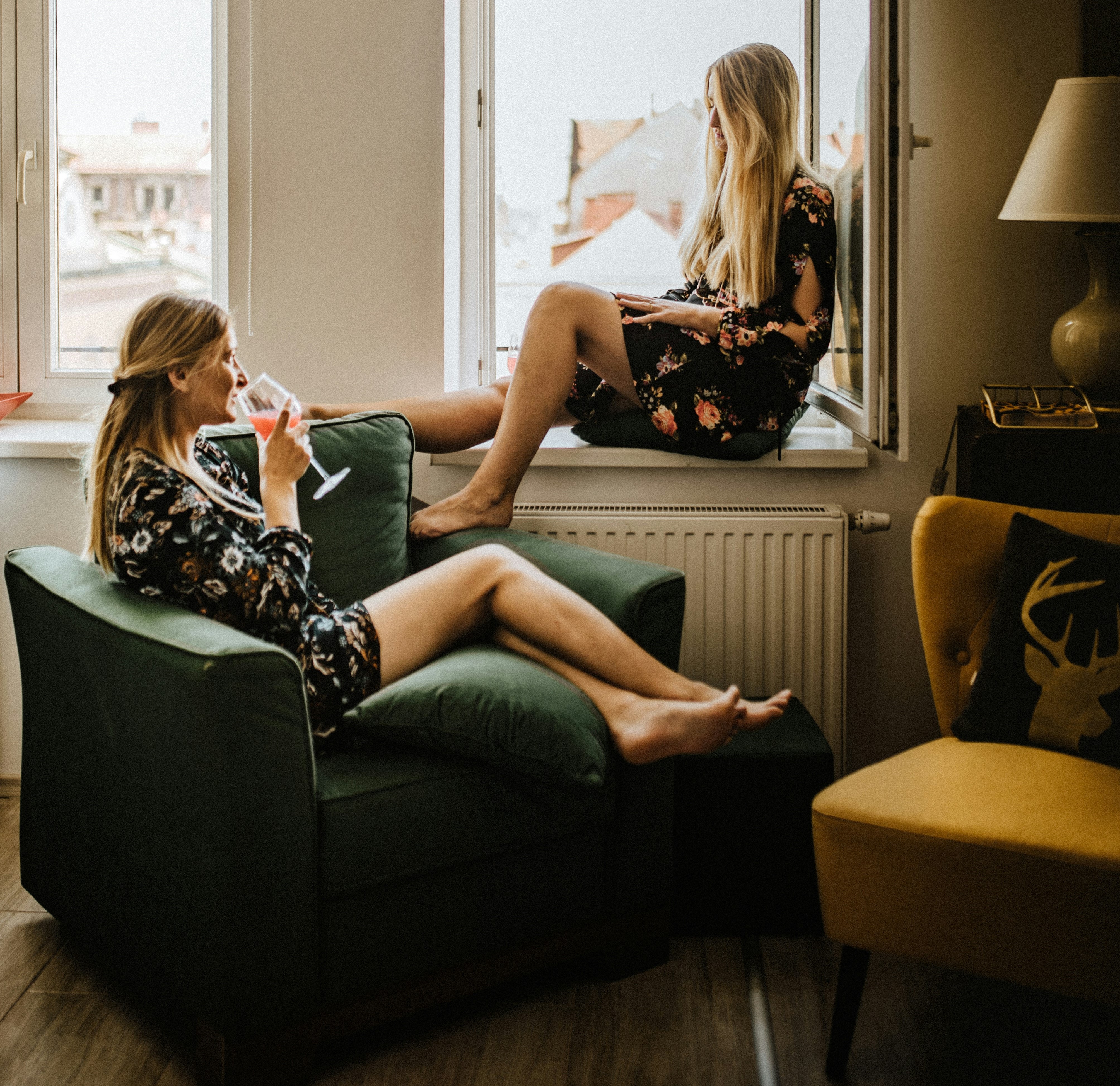 Two women in their living room talking and drinking wine.