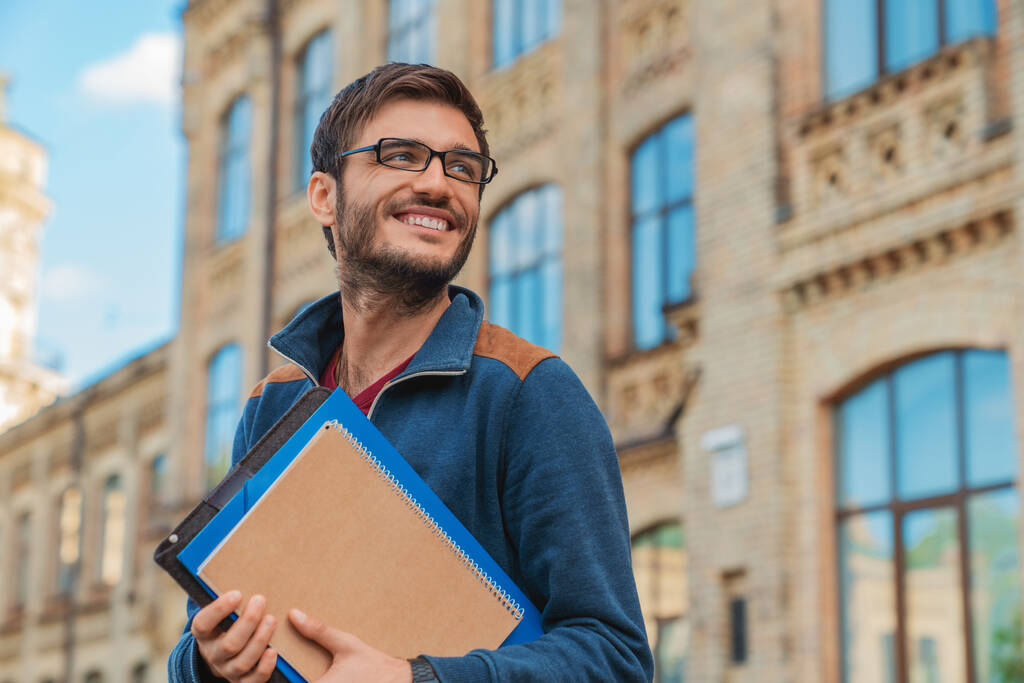 College student standing in front of a university building on the way to class.