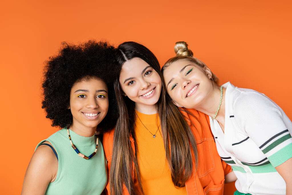 Three teen girls in front of an orange background.