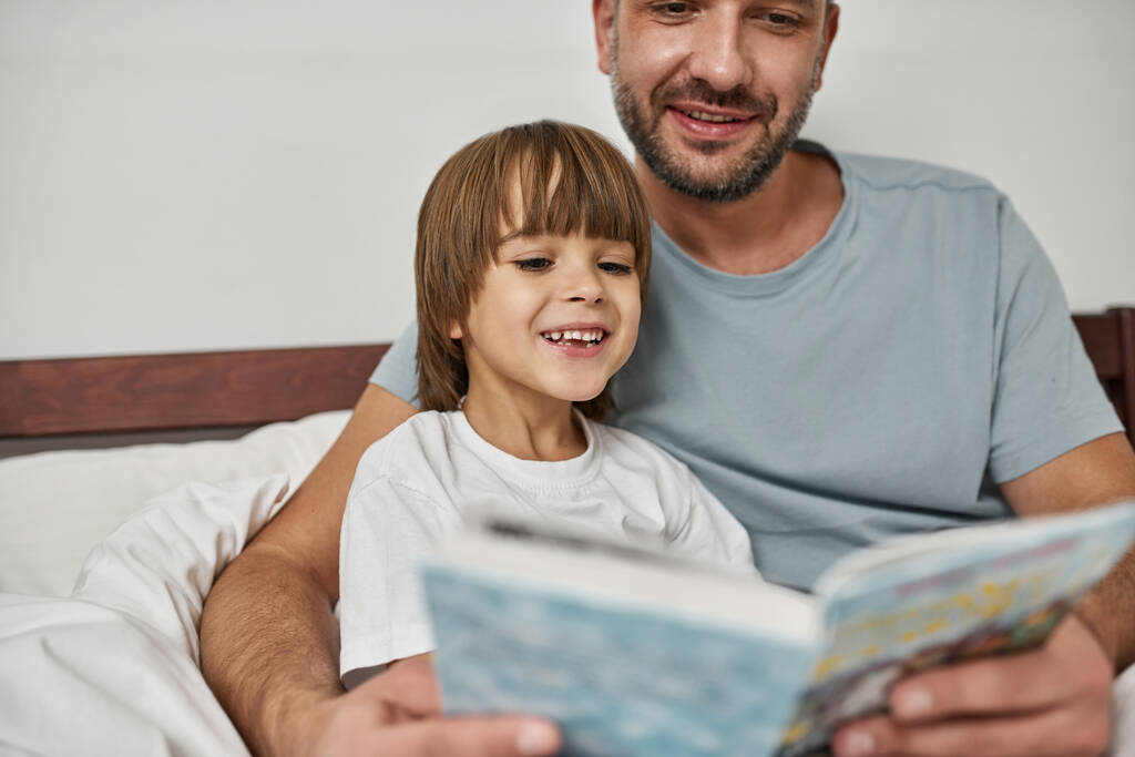 Father and son reading in bed.