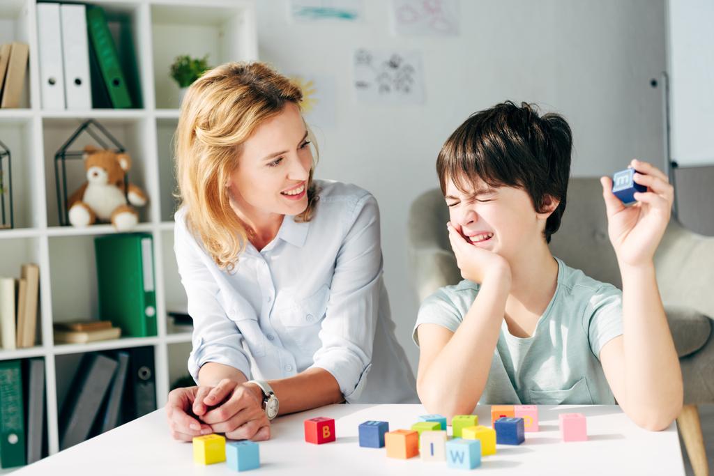 A woman helping a young boy with autism learn through play.