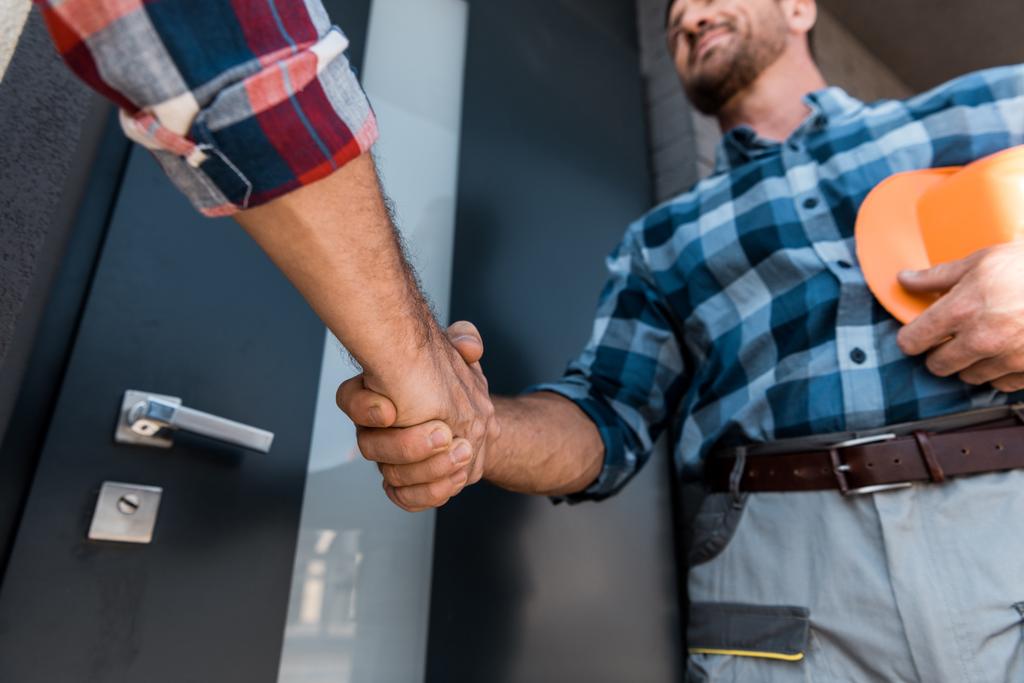 Two men shake hands at the front door.