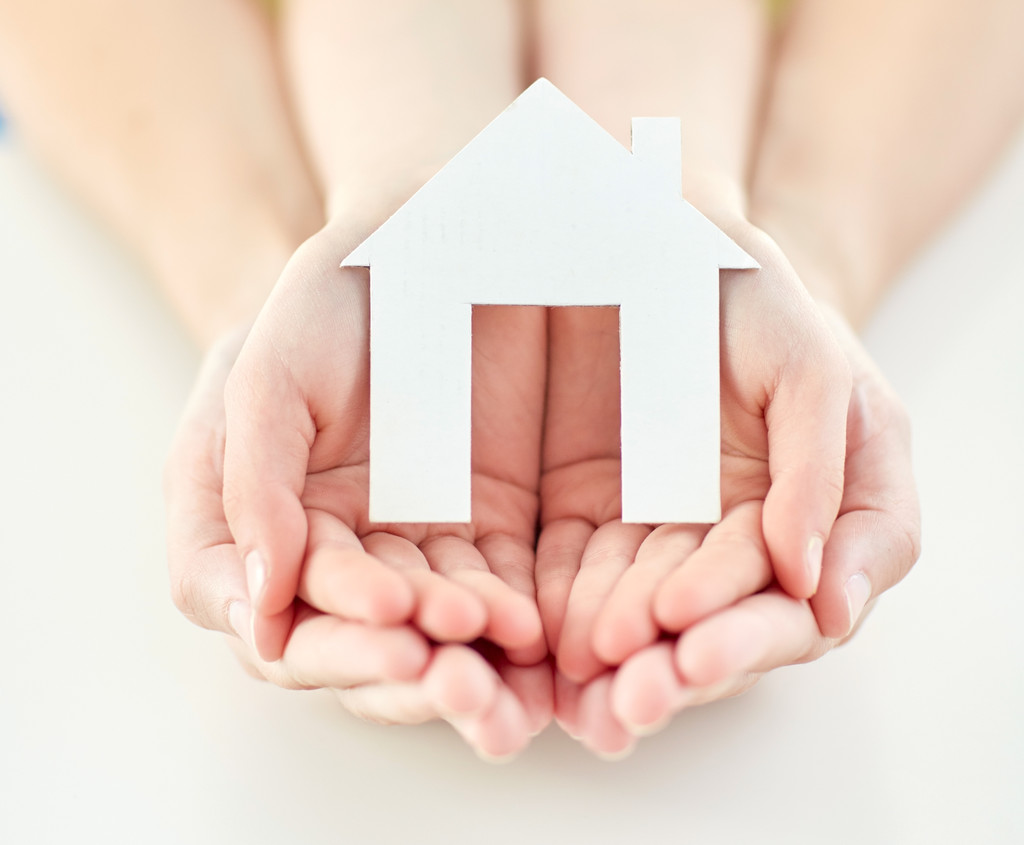 Two people's hands holding a silhouette of a home as a show of a safe home.