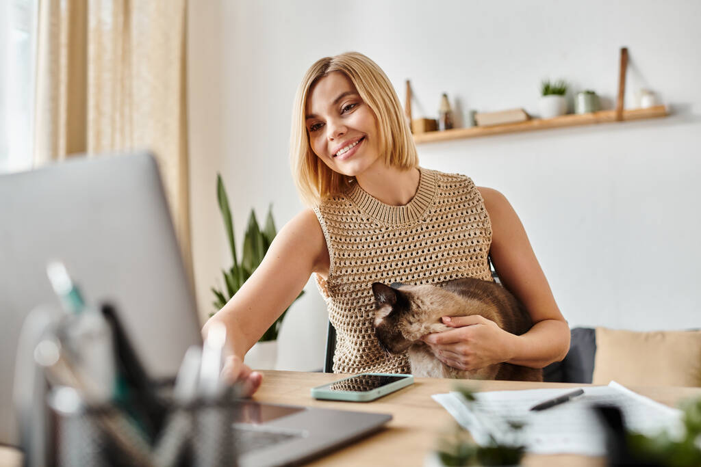 Woman safe at home with her cat as she works on her laptop.