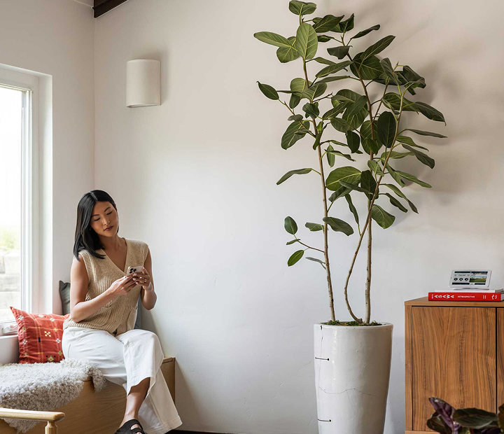 Woman sitting near window with panel on desk nearby