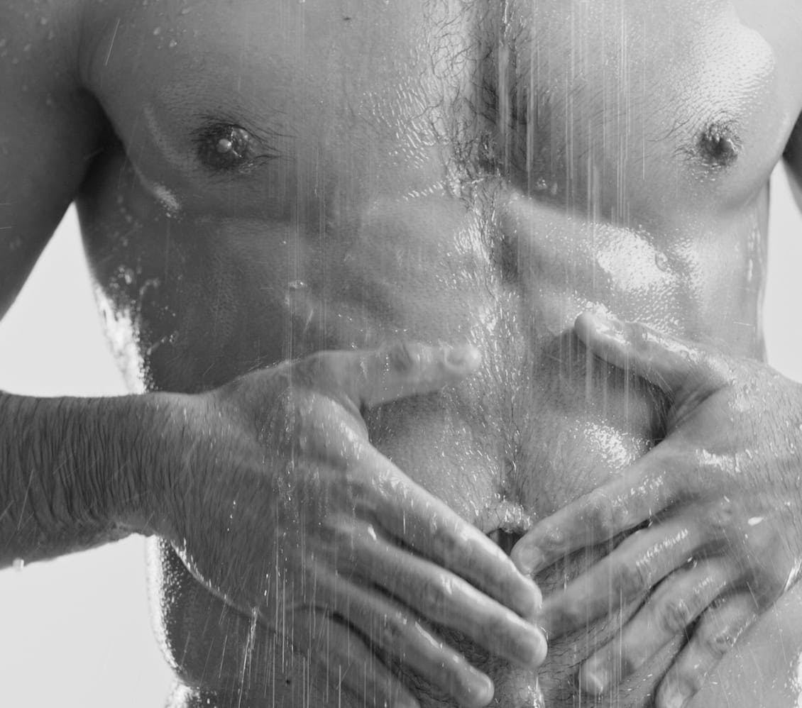 man touching abs in shower