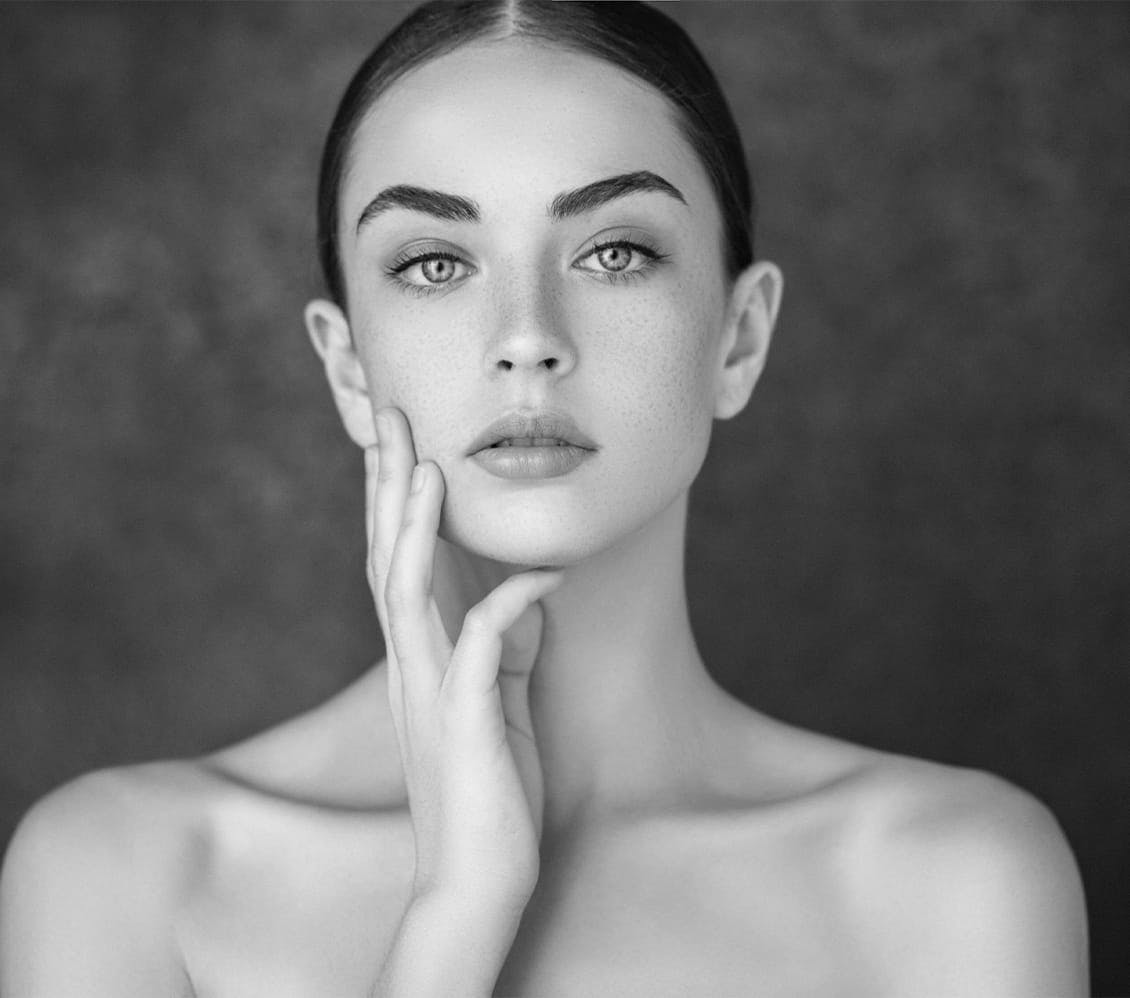 black and white photo of a woman touching her face