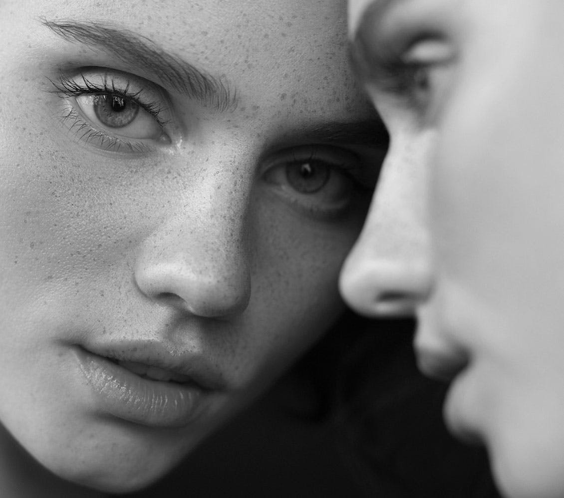 black and white photo of a woman leaning her face on a mirror