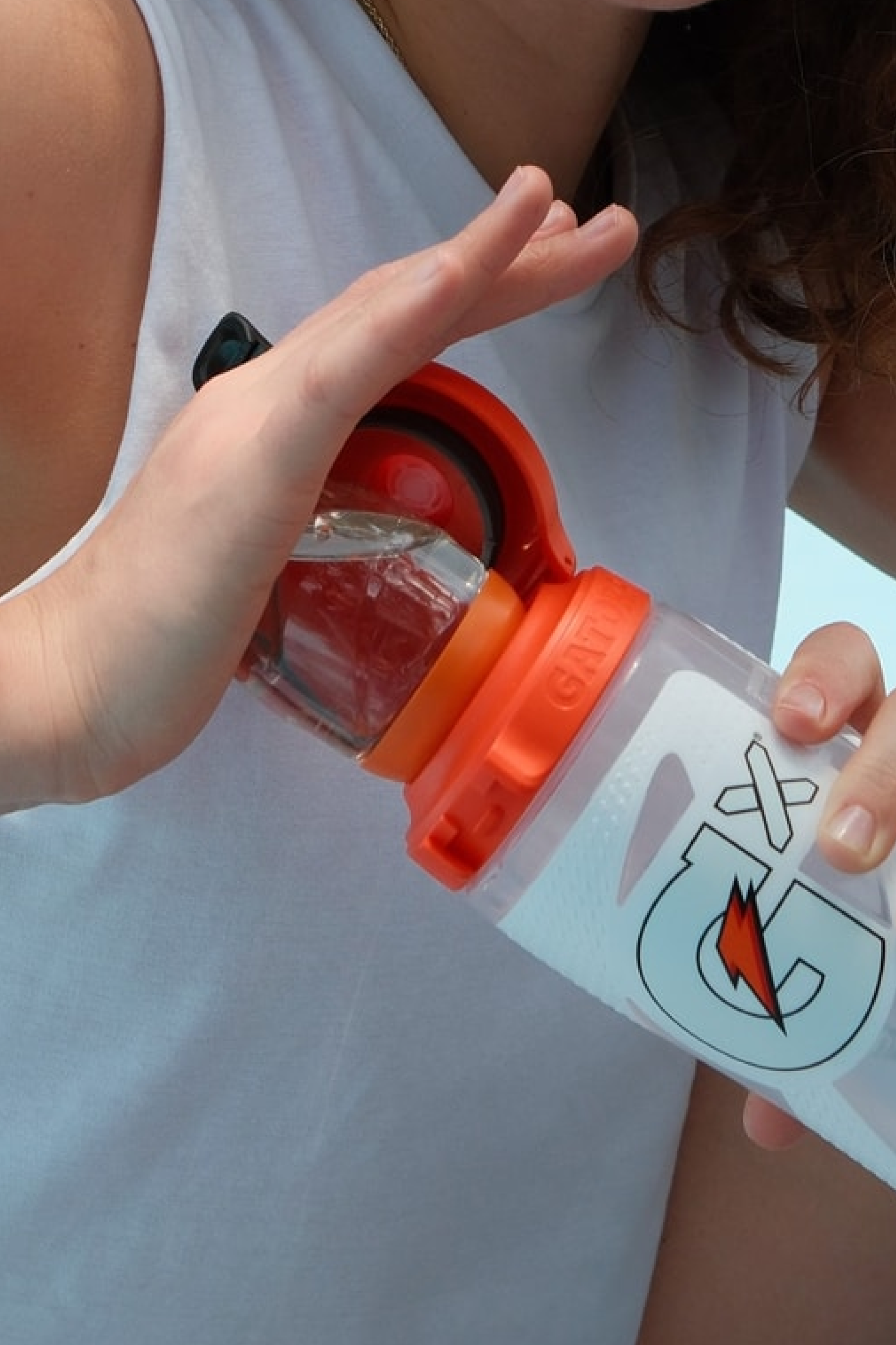 Athlete piercing a Gx Pod with the top of an open Gatorade Bottle