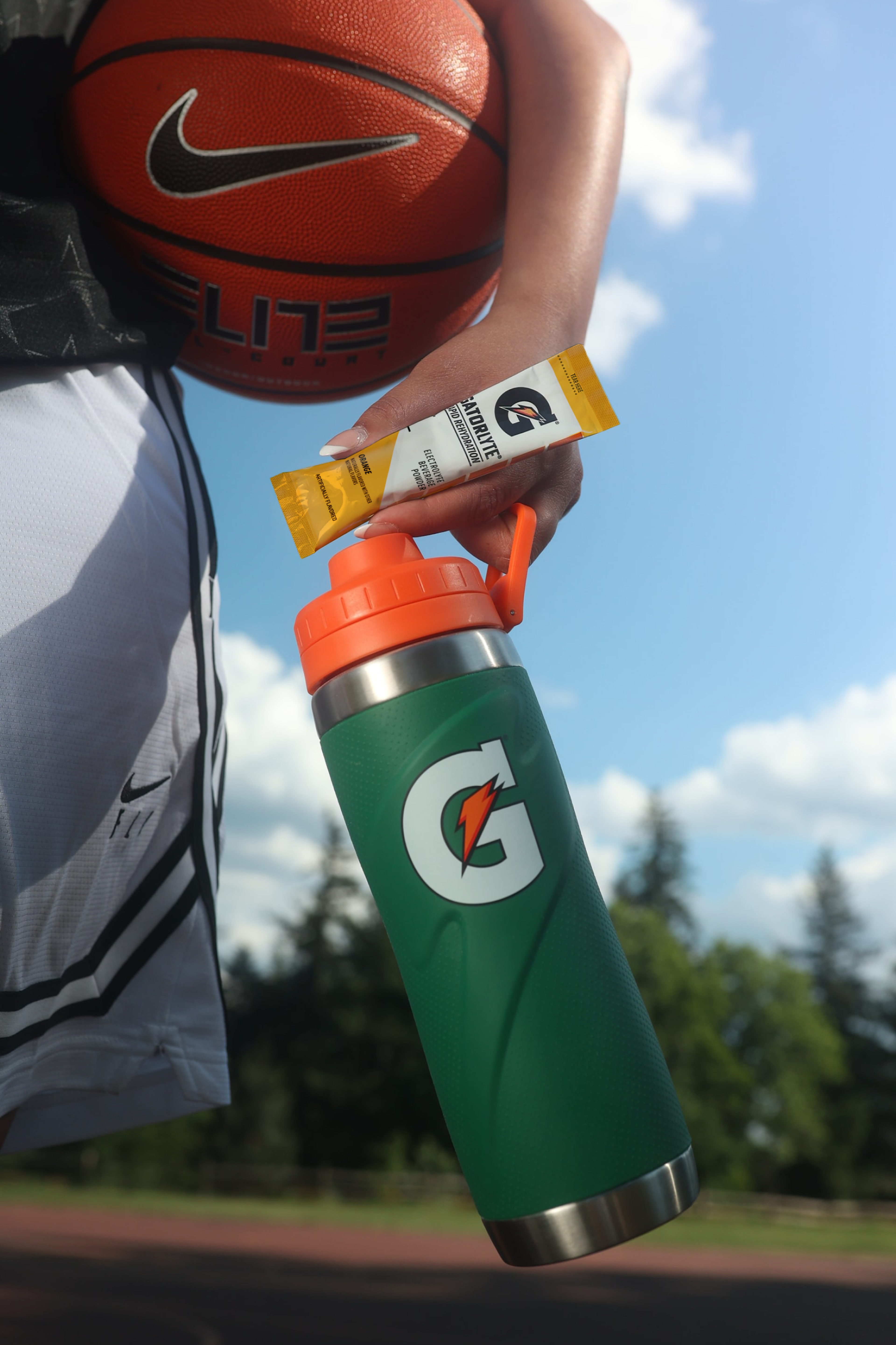 Athlete holding Gatorlyte orange single serve packet with Gx stainless steel bottle