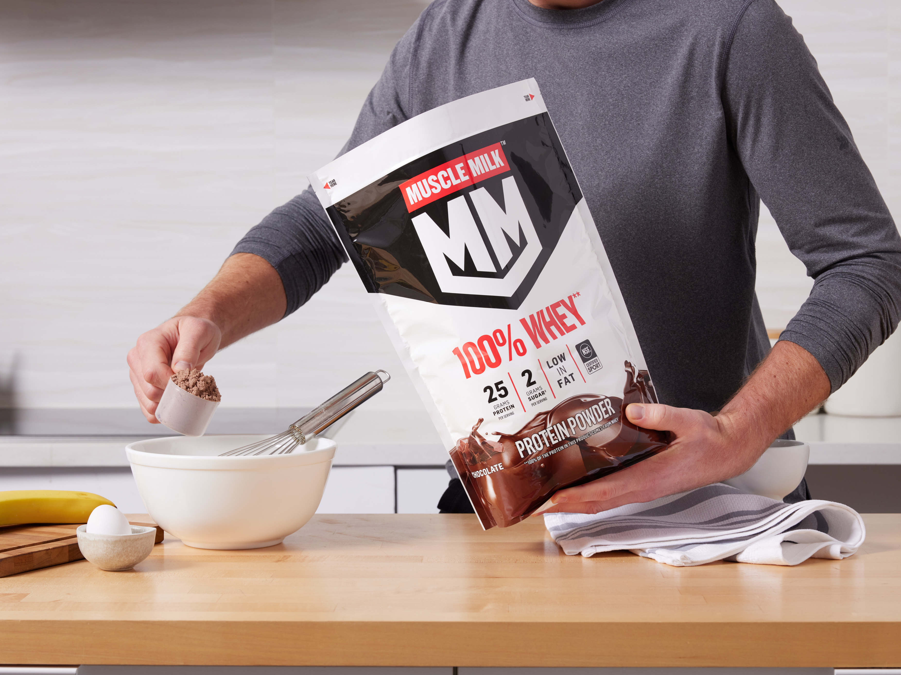 Man adding Muscle Milk 100% Whey Protein Powder to a bowl