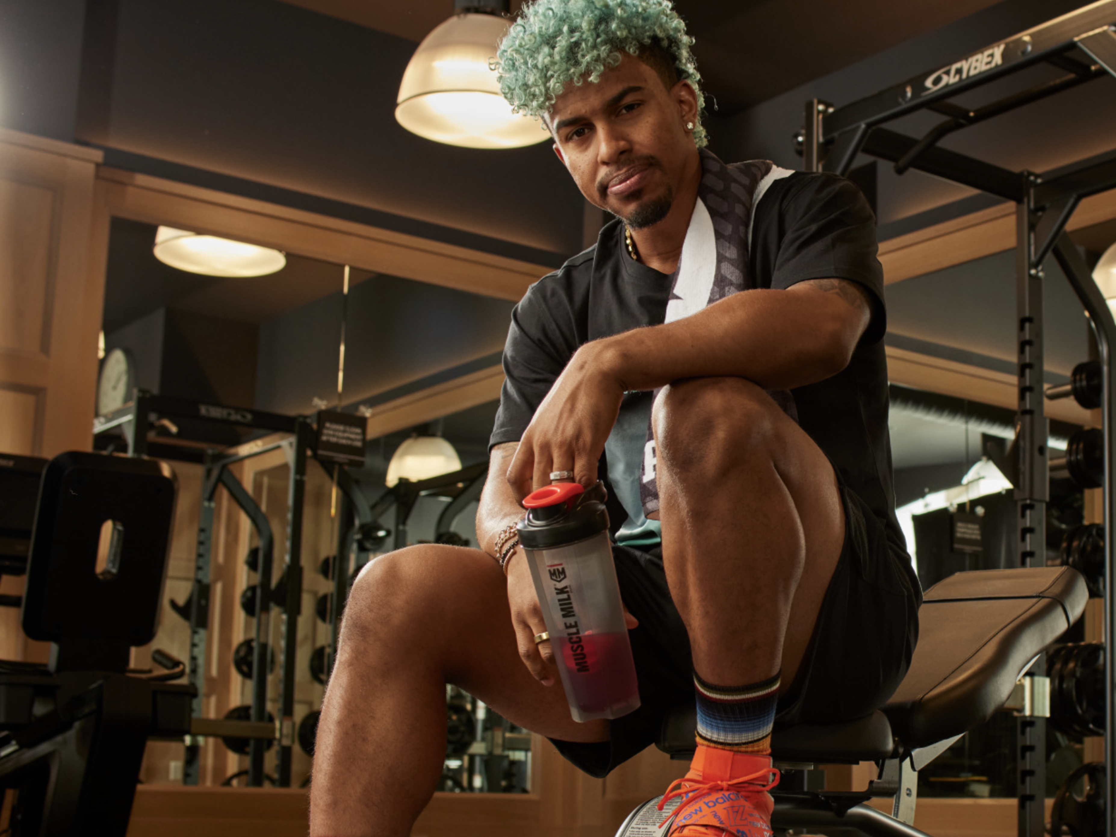 Athlete holding Muscle Milk shaker bottle in gym