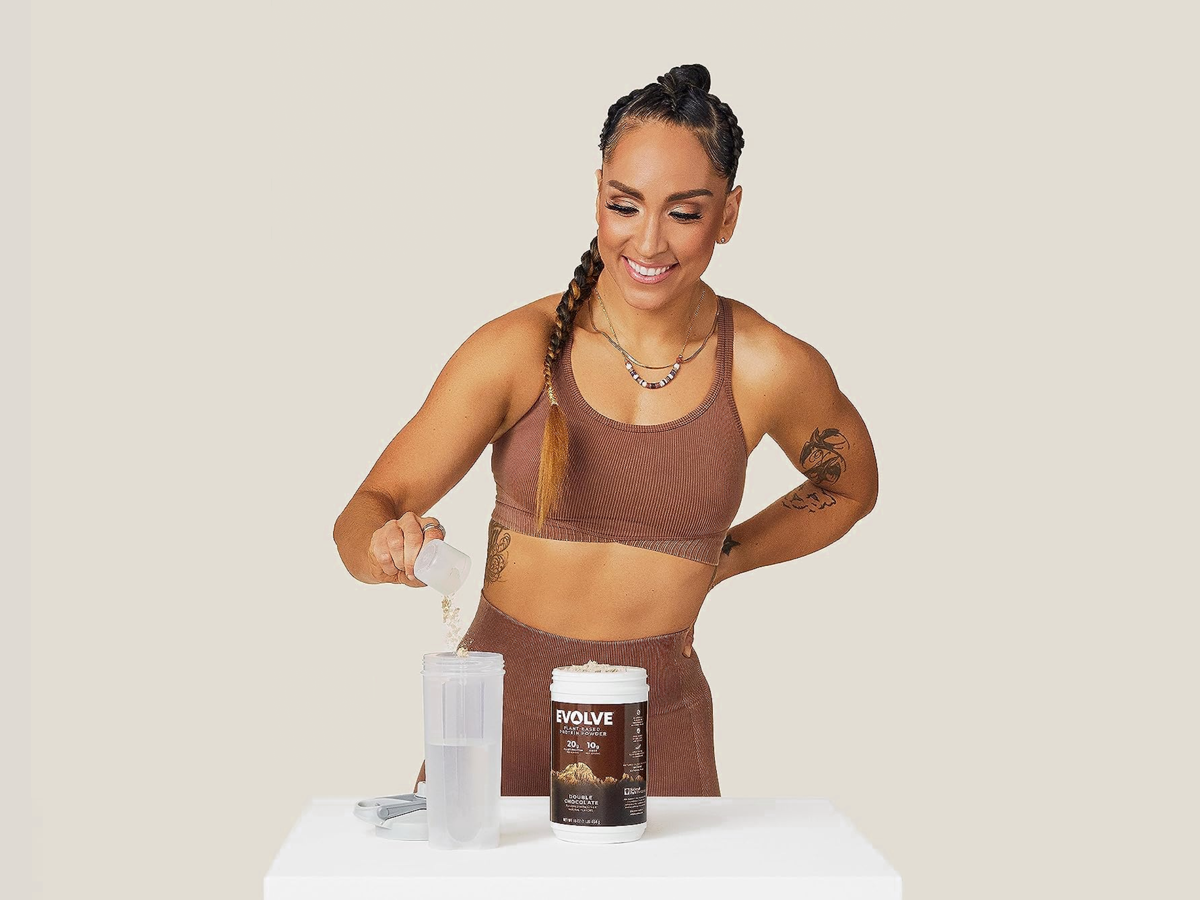 Woman adding Evolve Plant-Based Protein Powder to a Gatorade Shaker Bottle