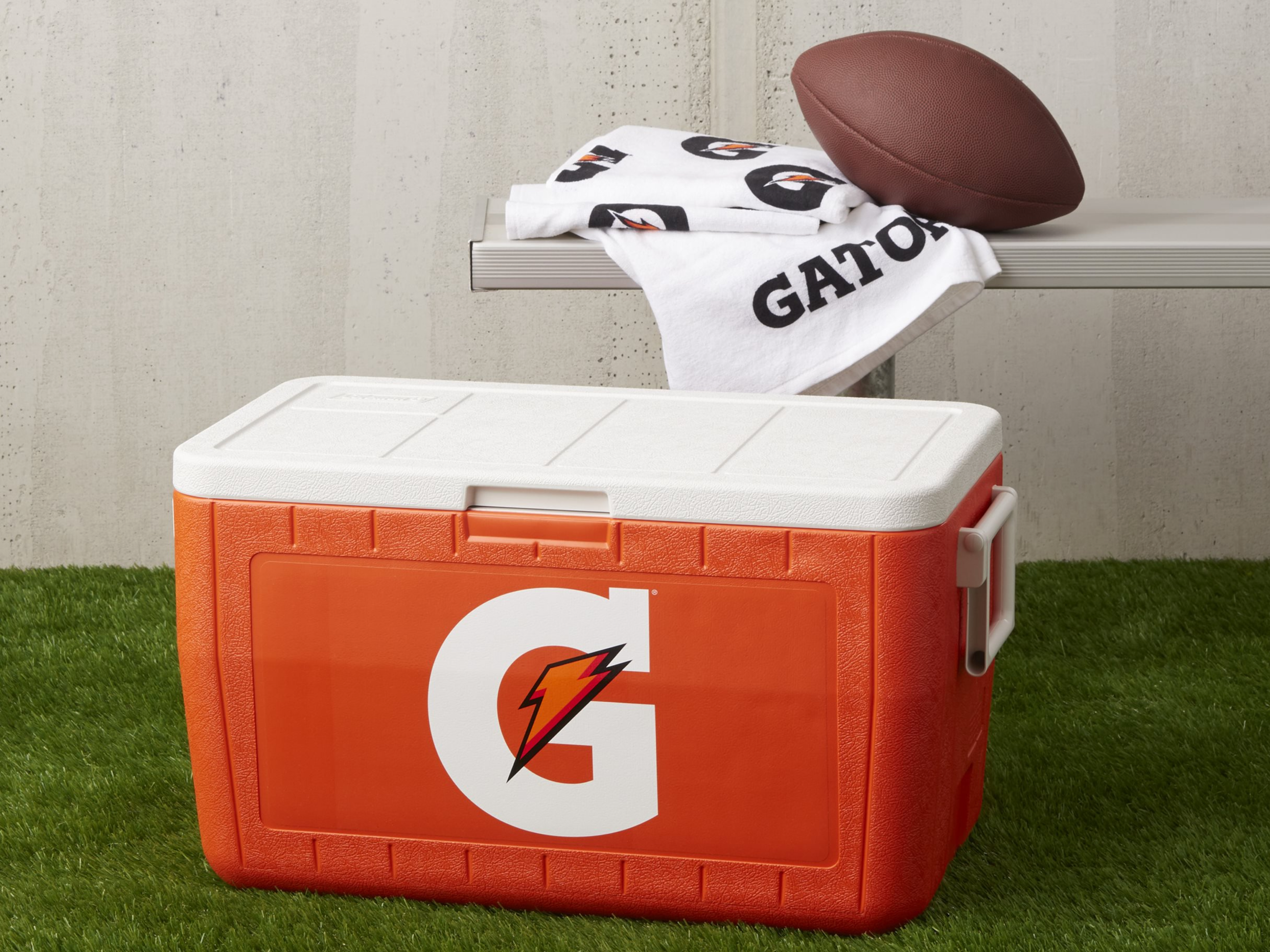 Gatorade Ice Chest on turf next to a bench with a towel and football