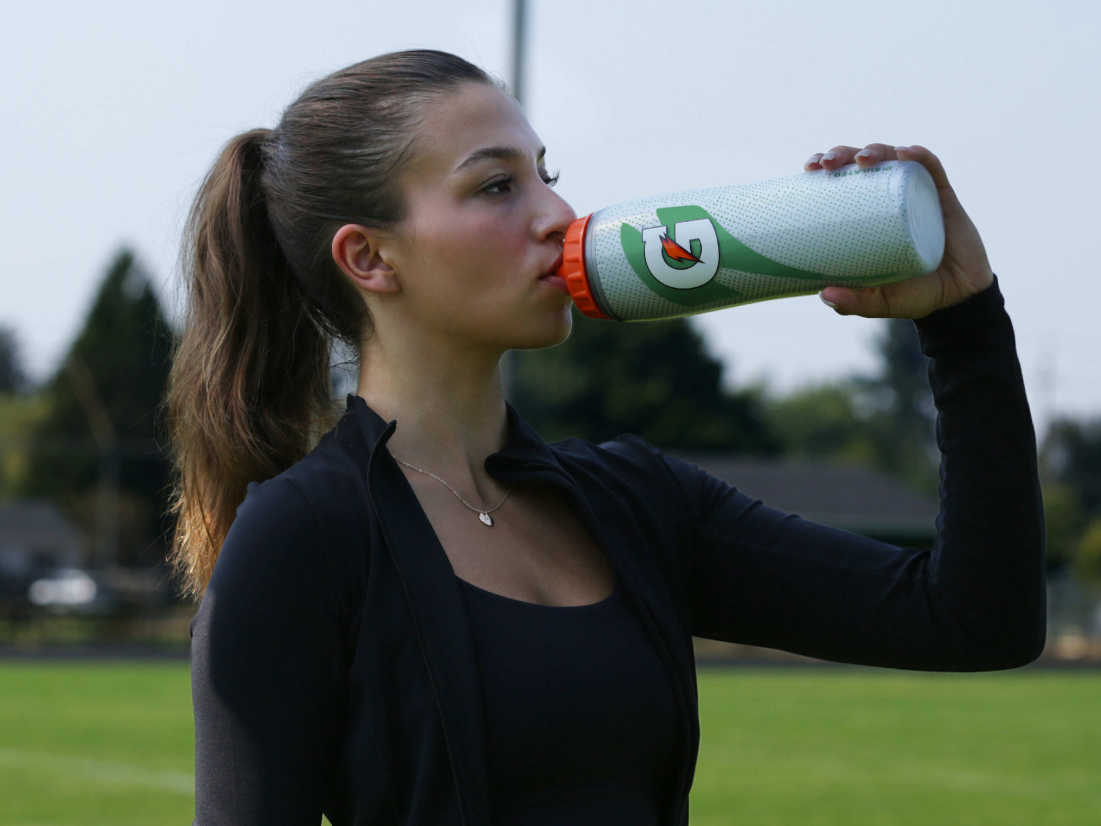 Athlete drinking out of silver insulated squeeze bottle