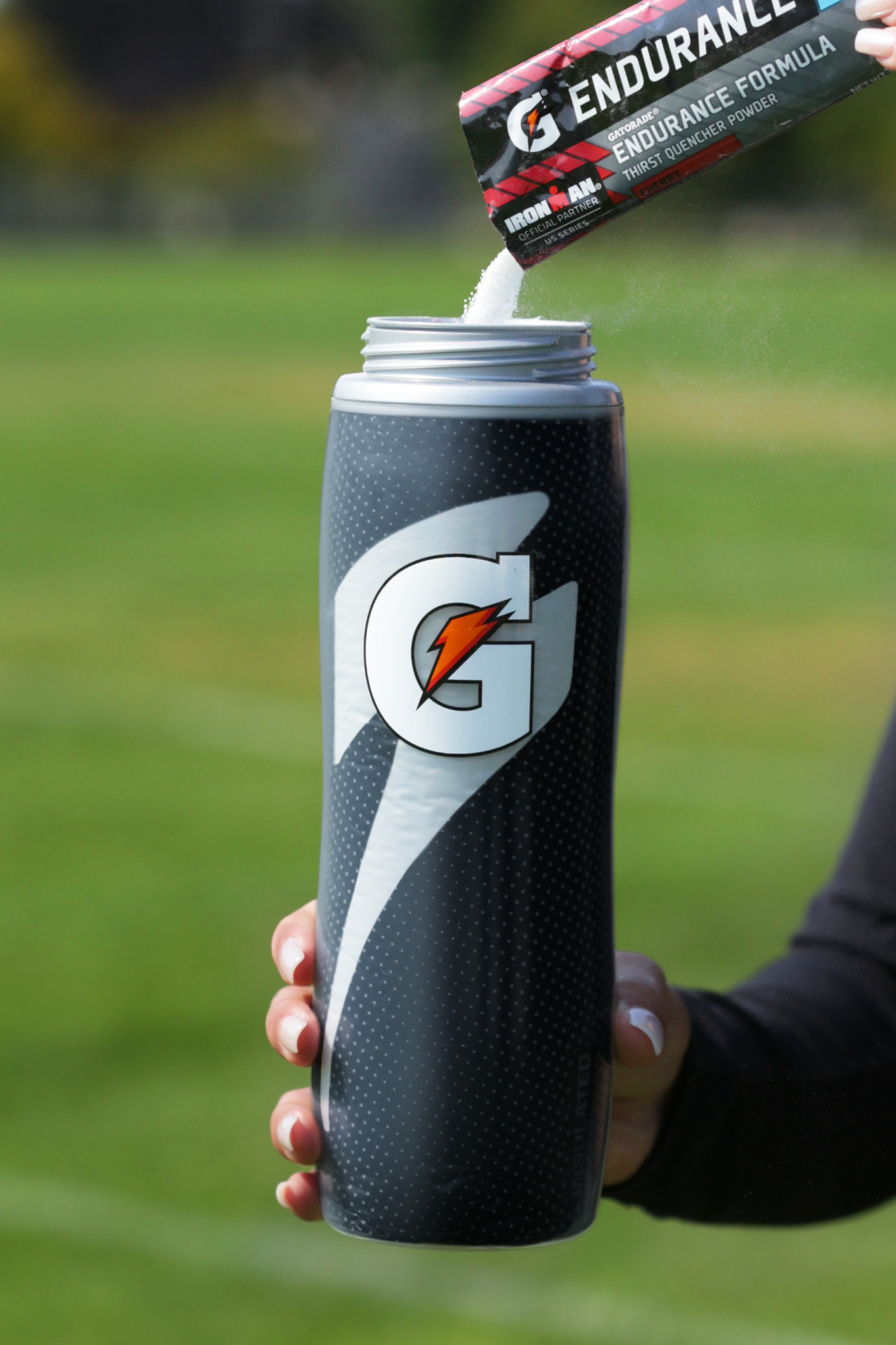 Powder being poured into black insulated squeeze bottle