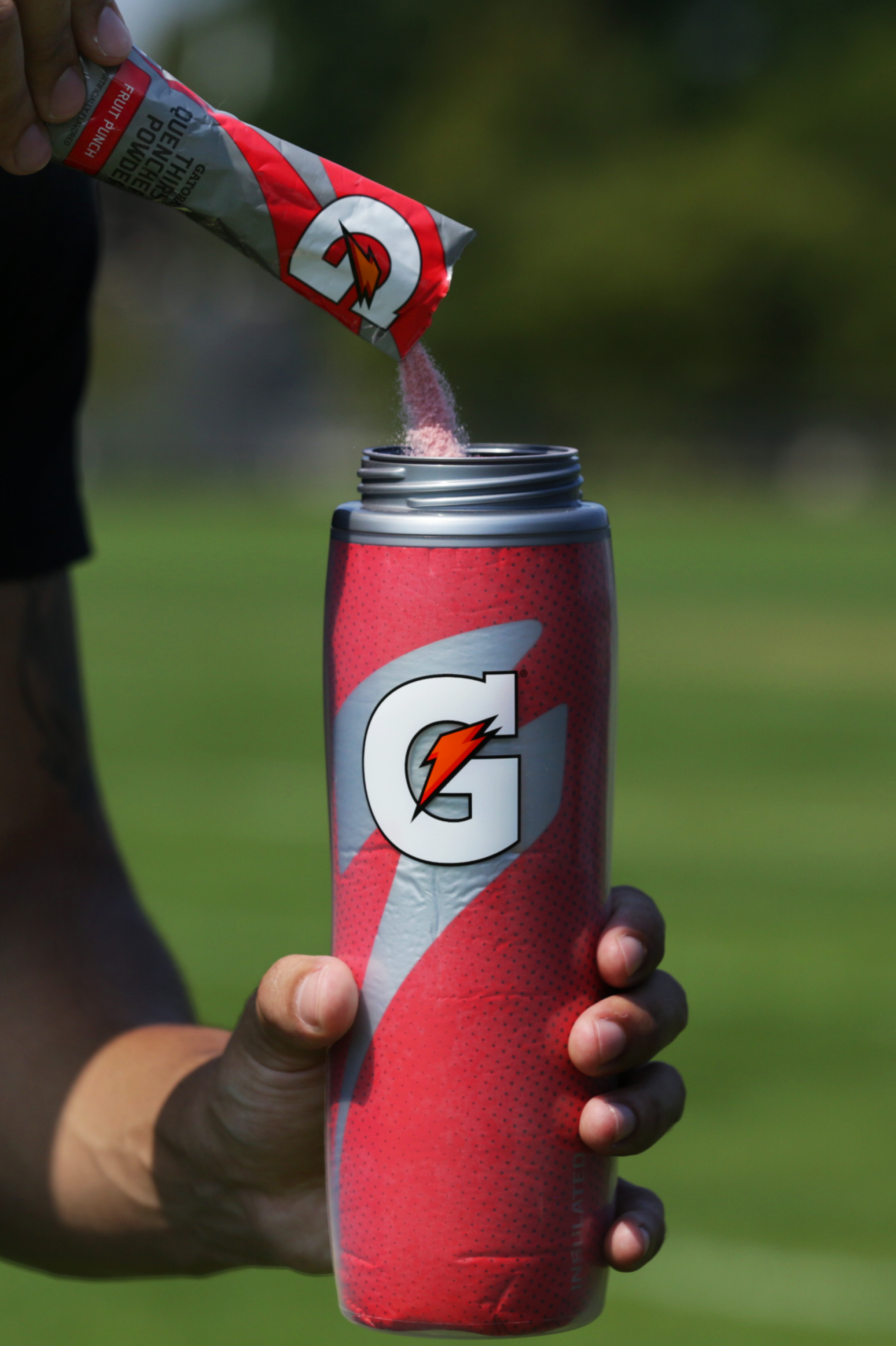 Powder being poured into Red insulated squeeze bottle