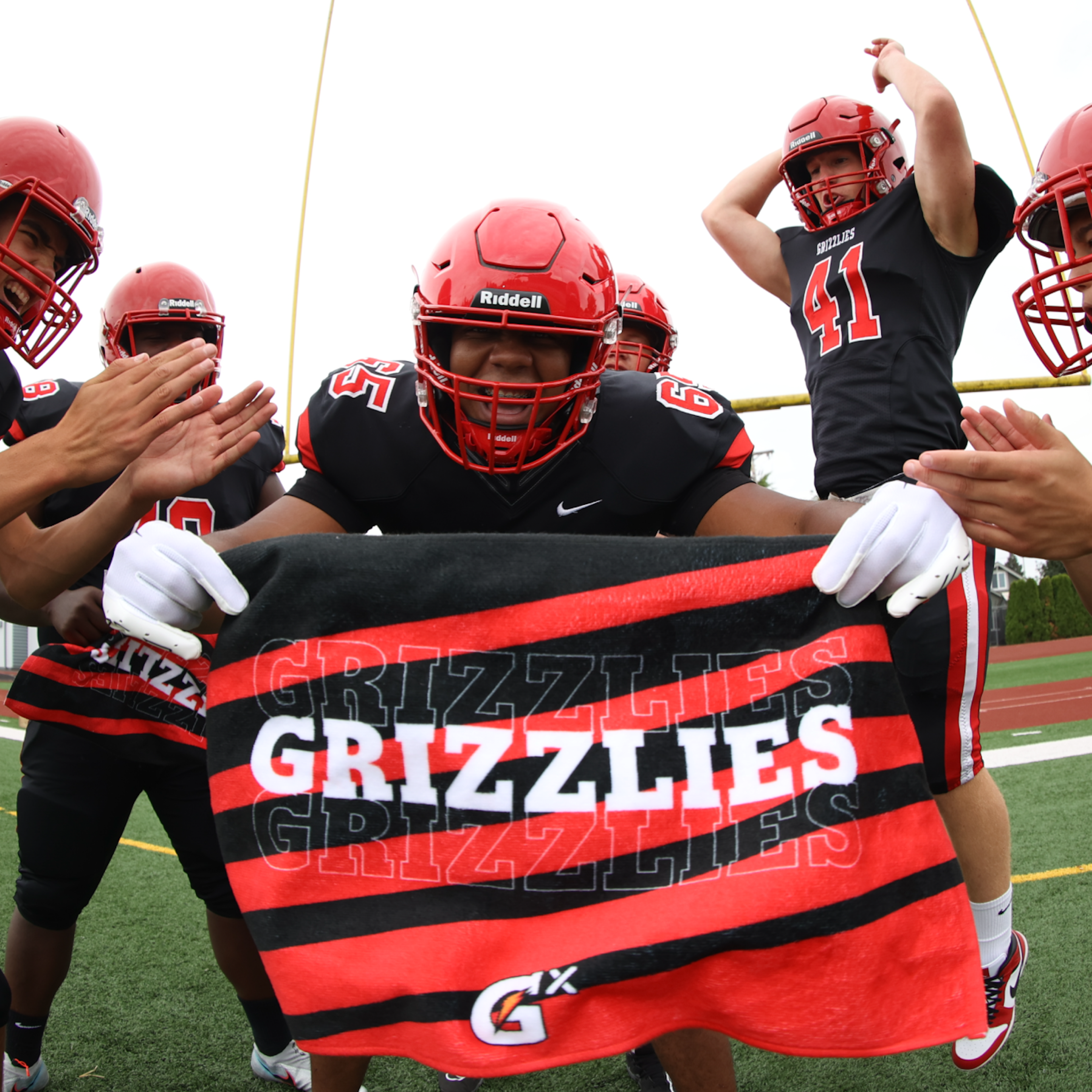 Social share image of football player holding a custom Gatorade ID Towel on a football field with teammates..