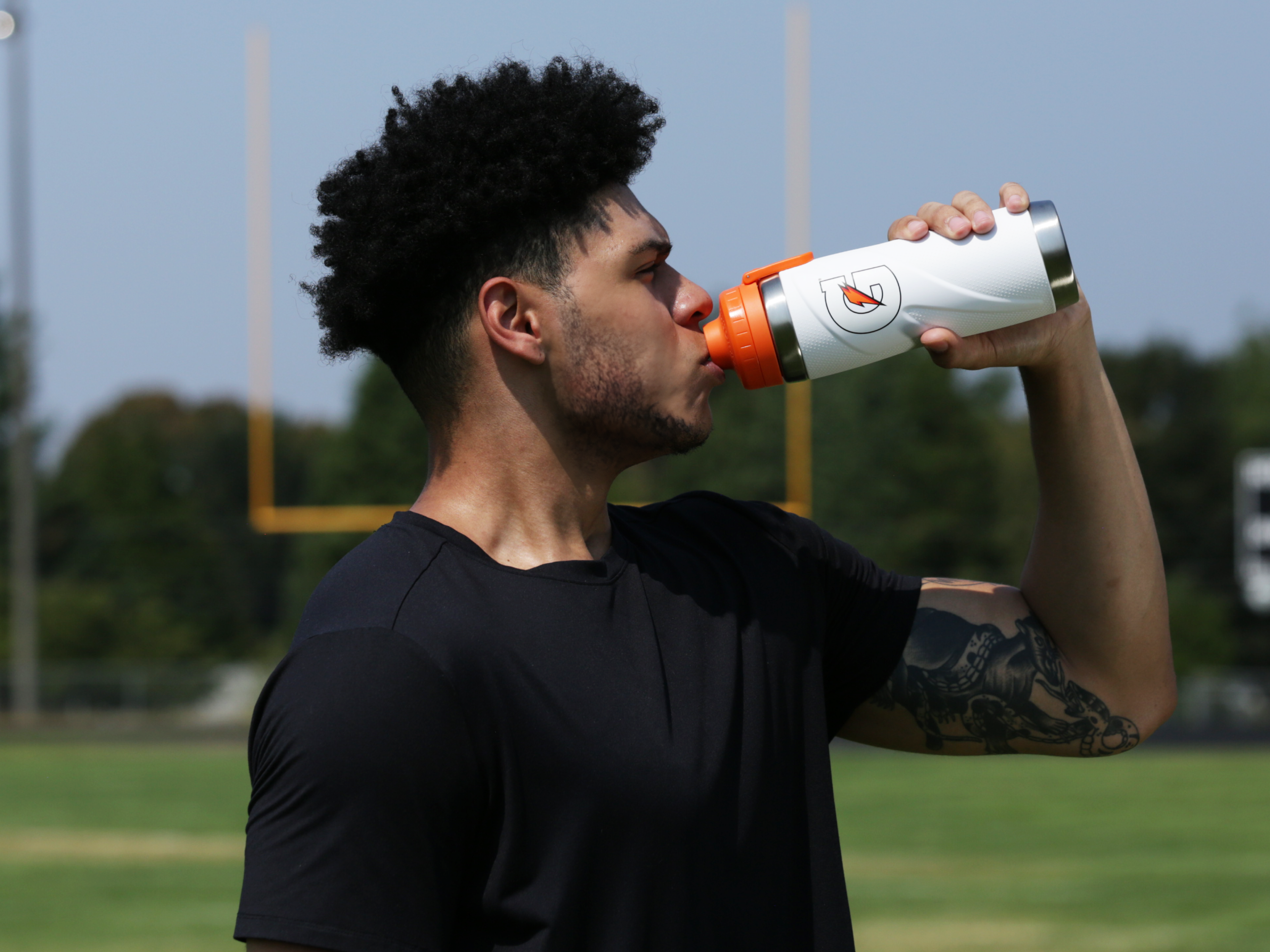 Athlete drinking from a White Gx Stainless Steel Bottle