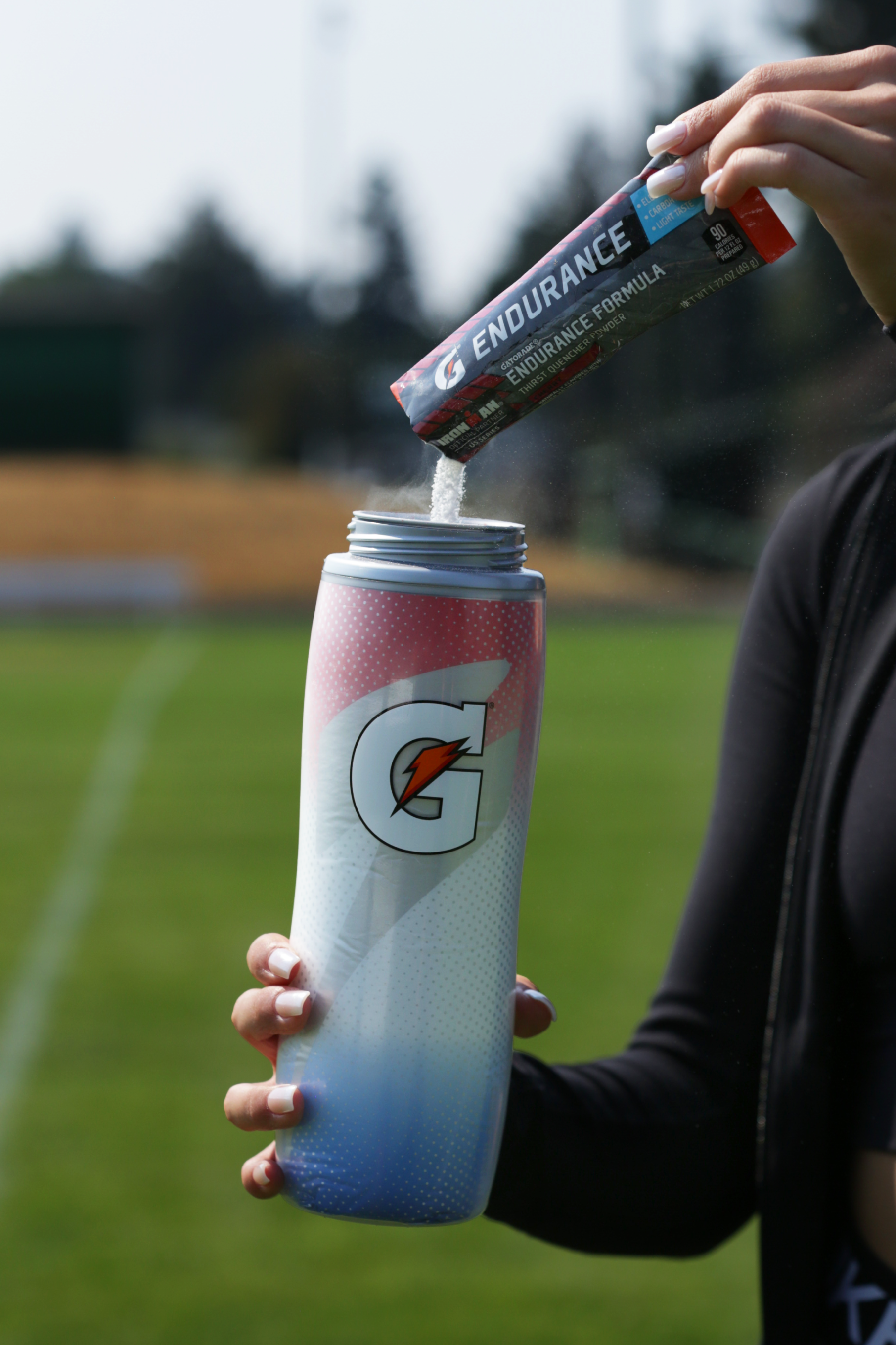 Athlete pouring Gatorade endurance powder into a Faded Flag Insulated Squeeze Bottle