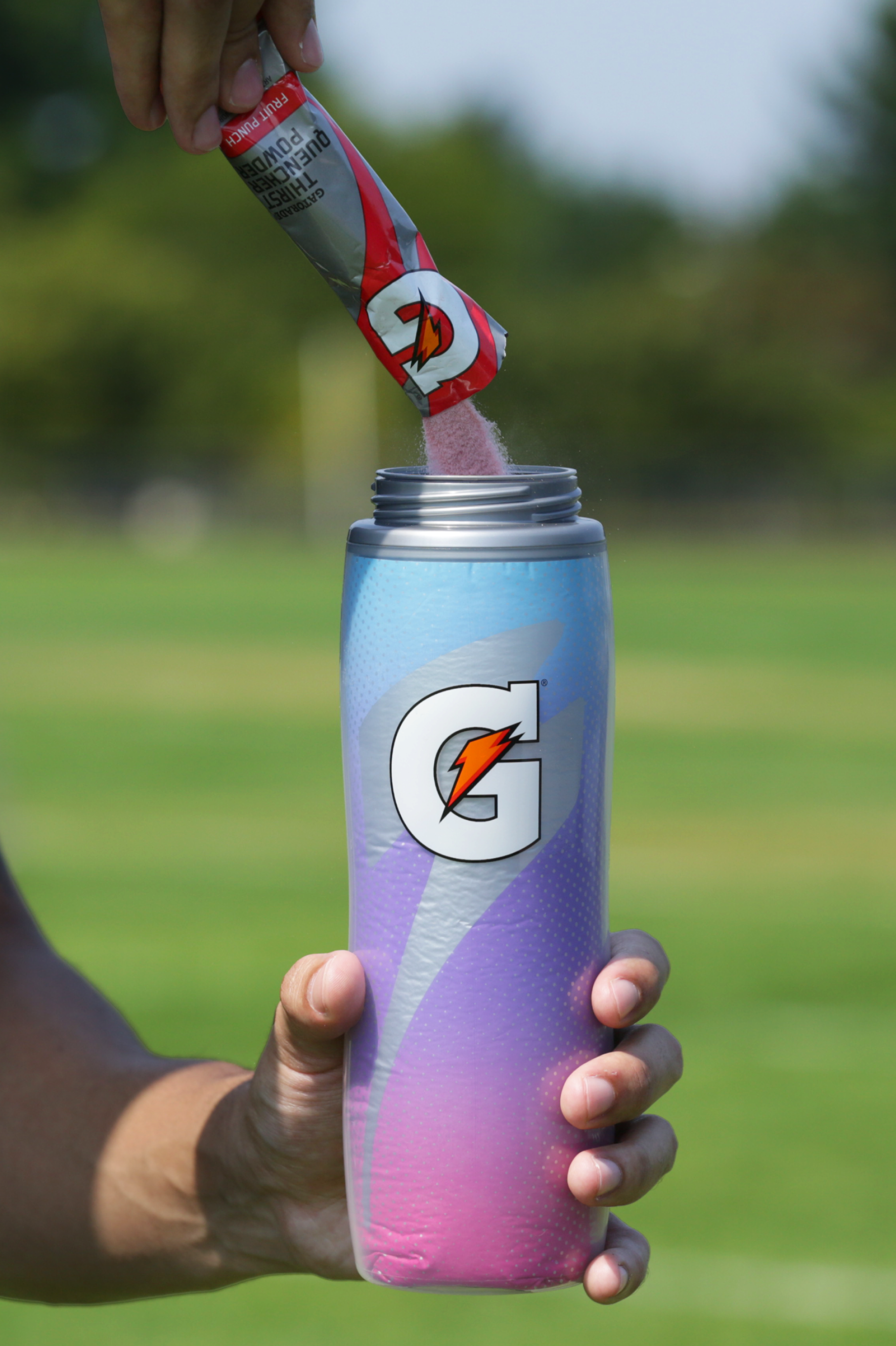 Athlete pouring Gatorade endurance powder into a Pink Sky Insulated Squeeze Bottle