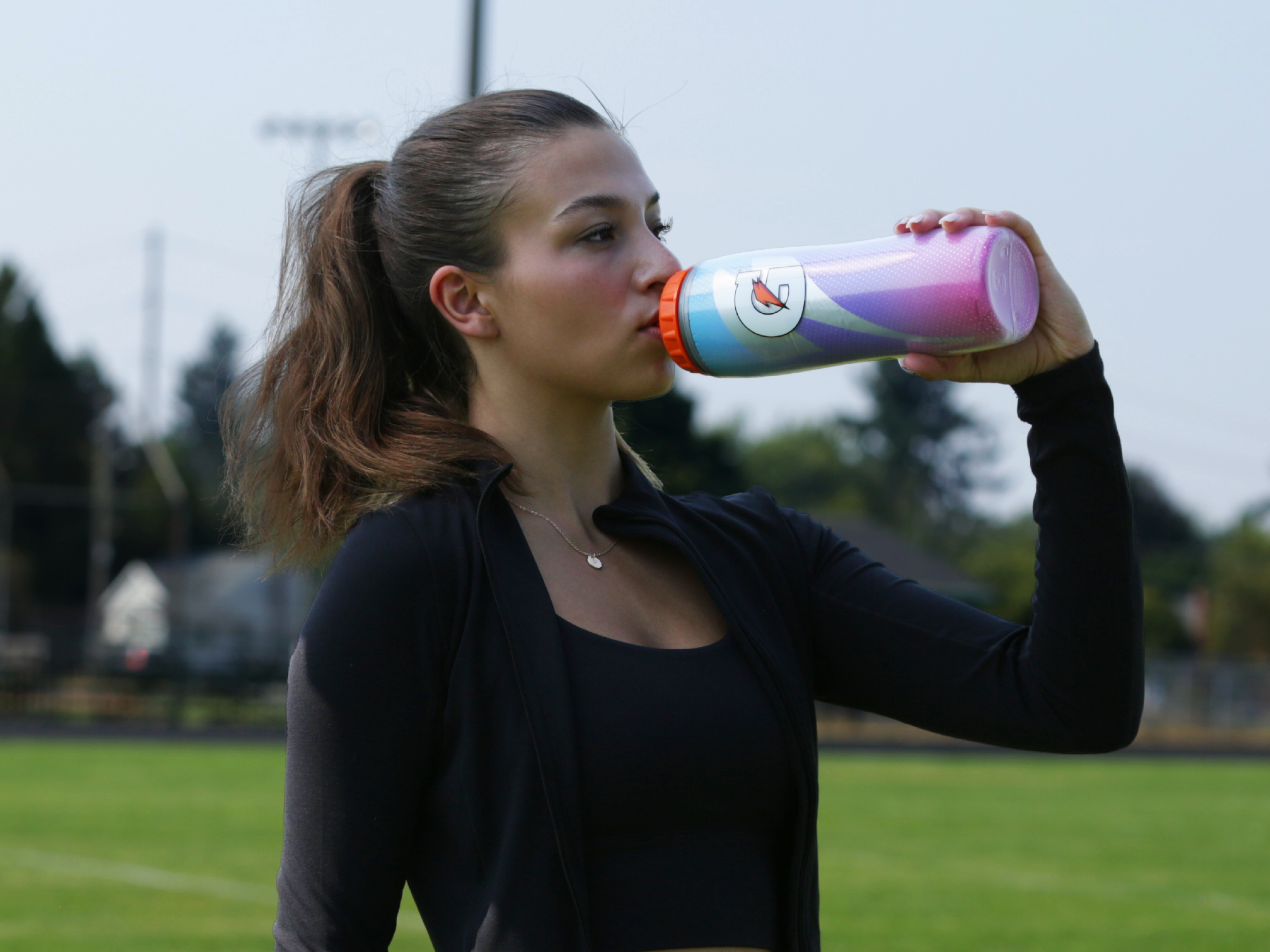 Athlete drinking from a Pink Sky Insulated Squeeze Bottle
