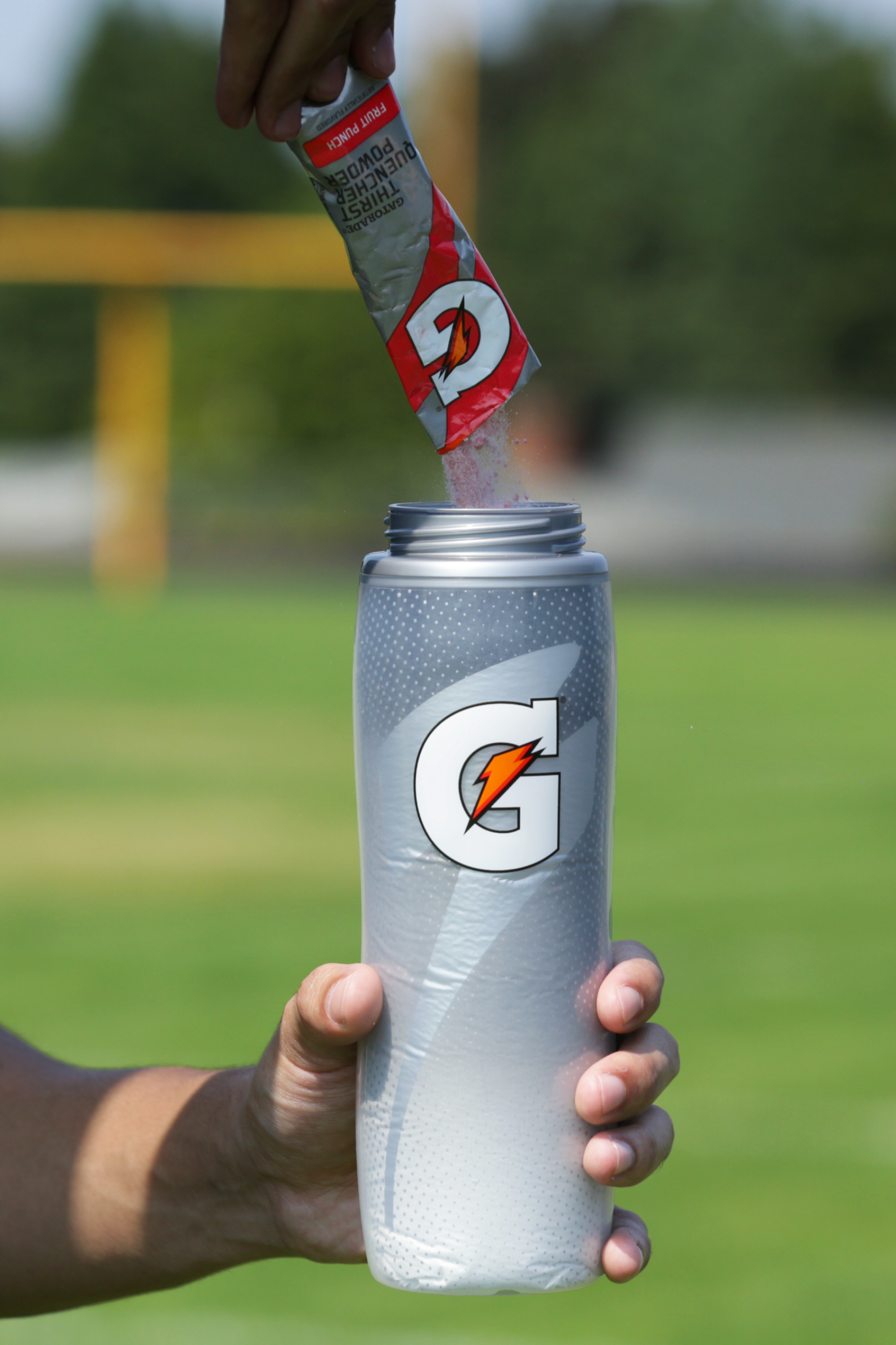 Athlete pouring Gatorade endurance powder into a Light Shadow Insulated Squeeze Bottle