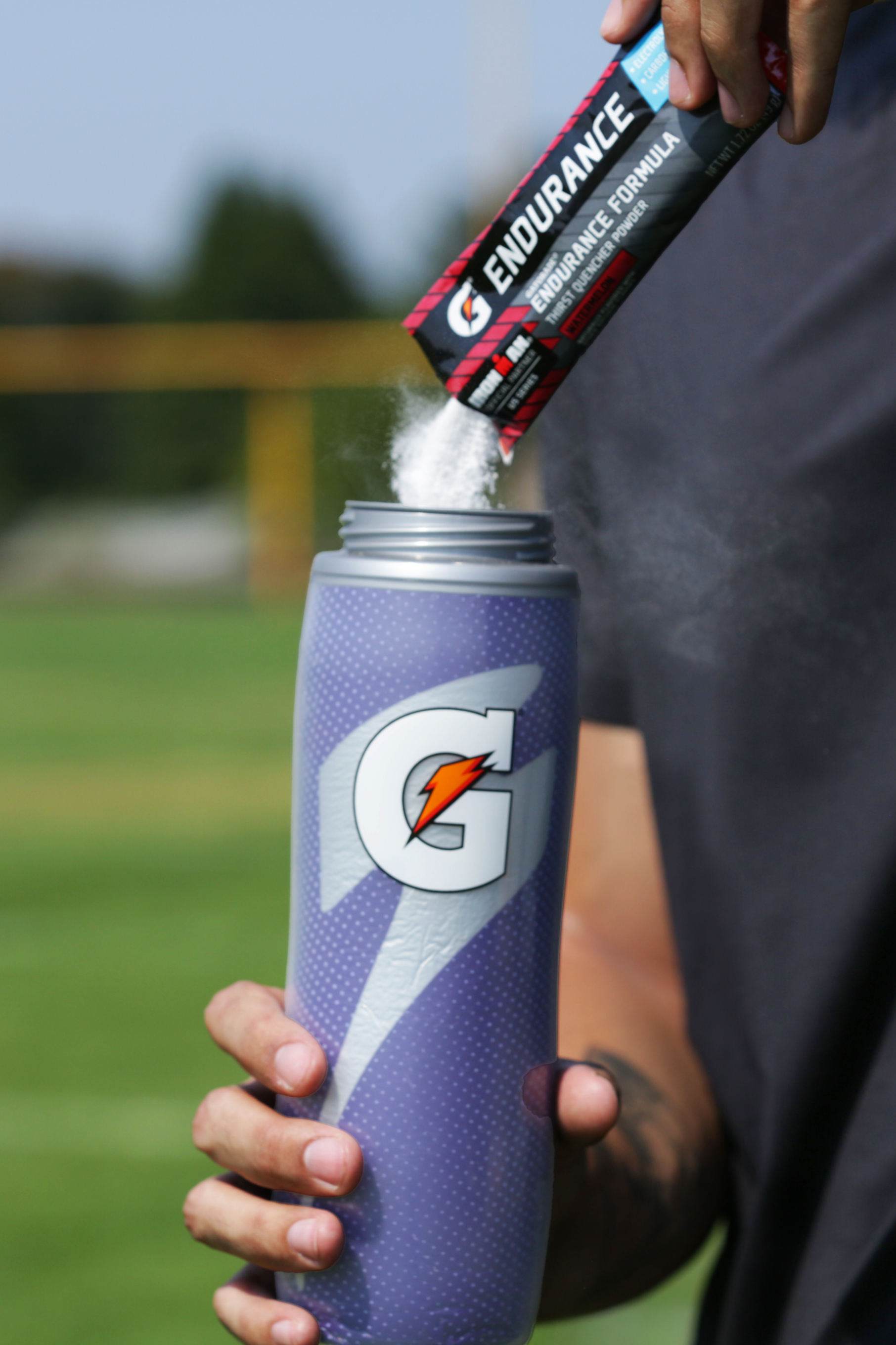 Athlete pouring Gatorade endurance powder into a Purple Insulated Squeeze Bottle